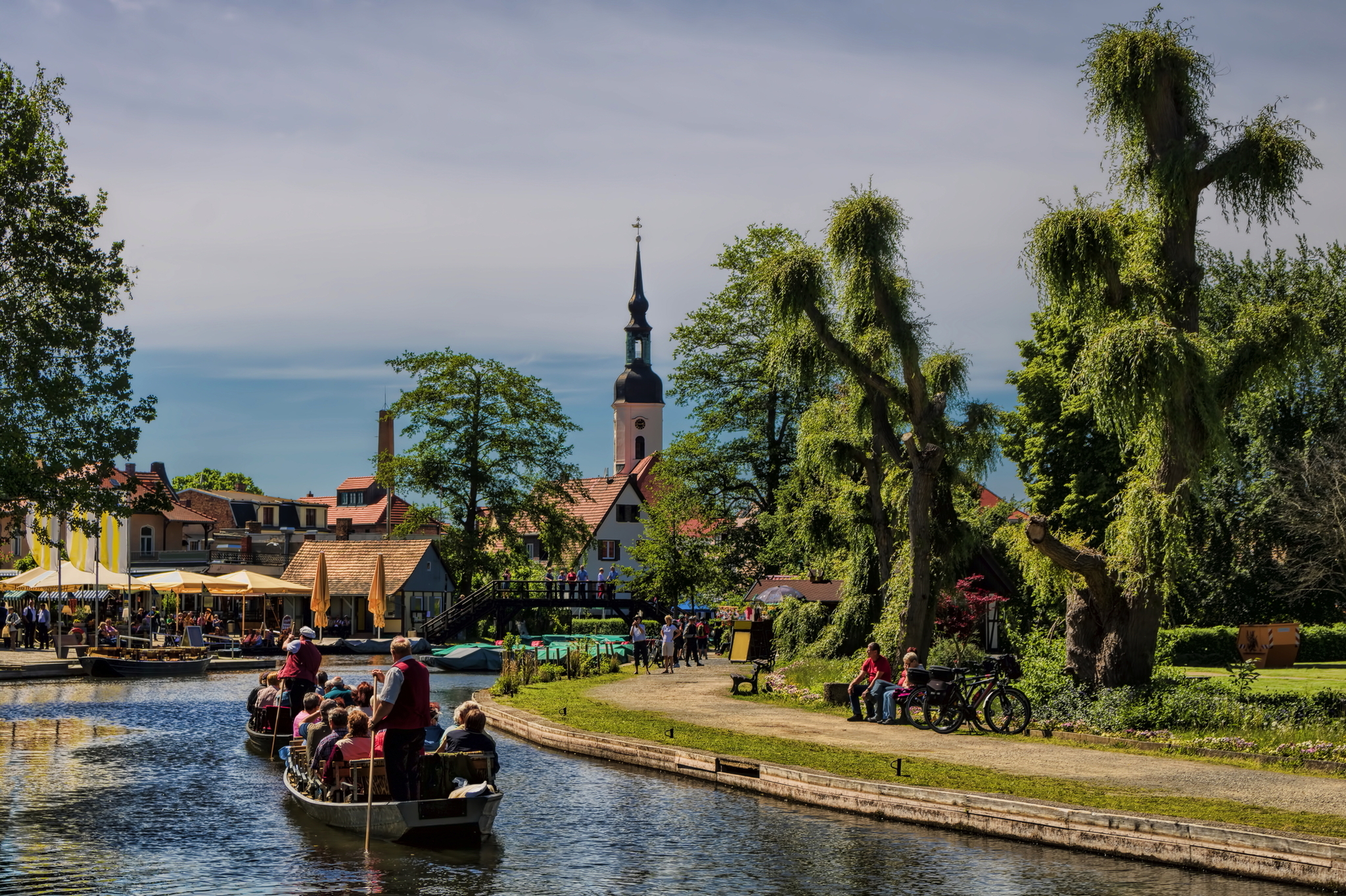 Bootsfahrt auf einem Fluss in einer malerischen Stadt mit Kirche und Bäumen.