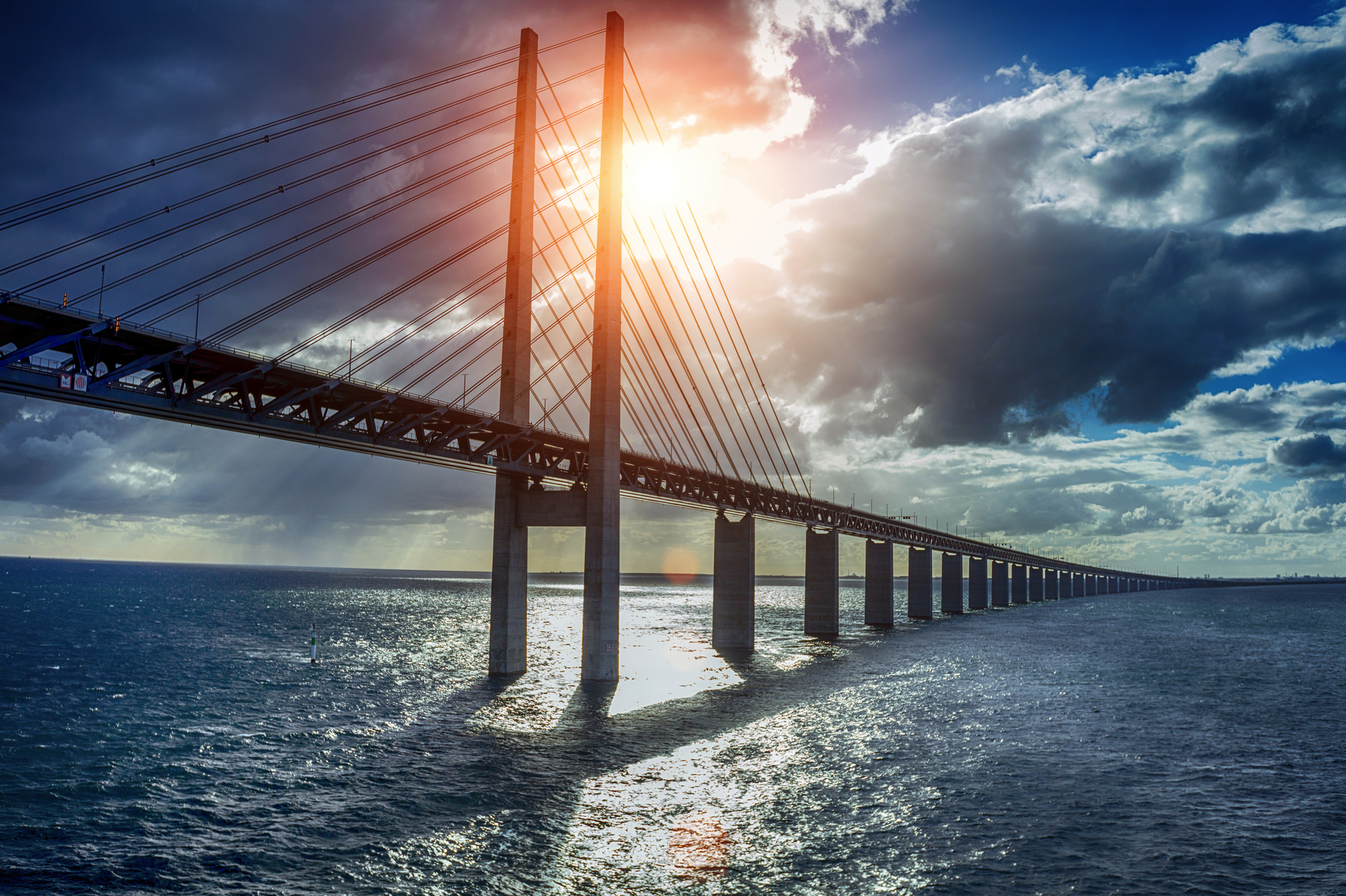 Lange Brücke über das Meer bei Sonnenuntergang mit Wolken am Himmel