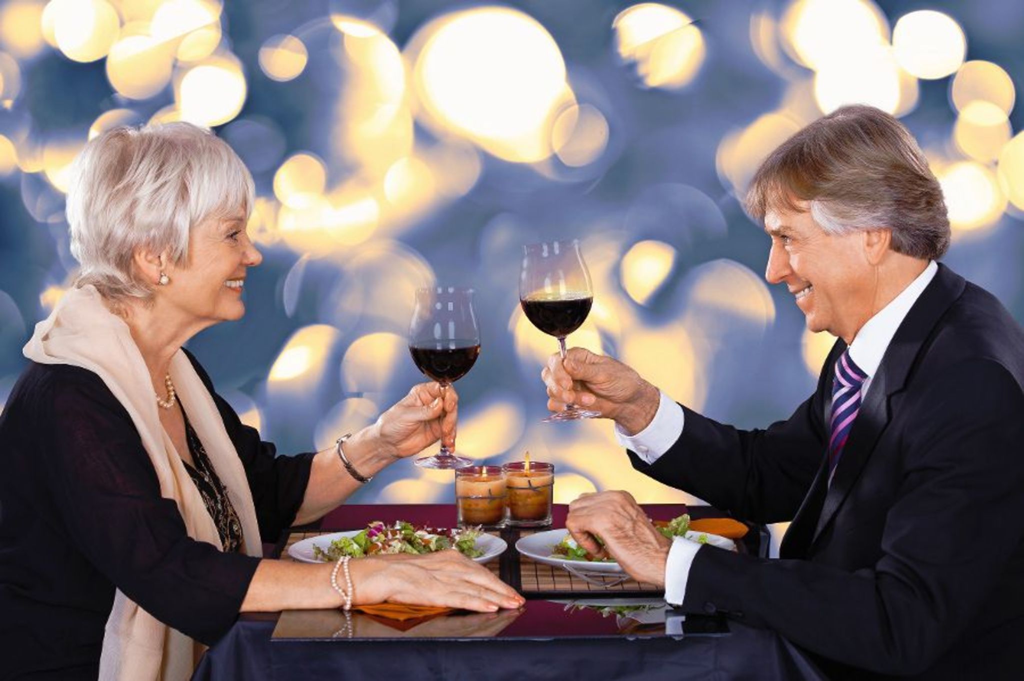Älteres Paar stößt beim Abendessen mit Rotwein an.