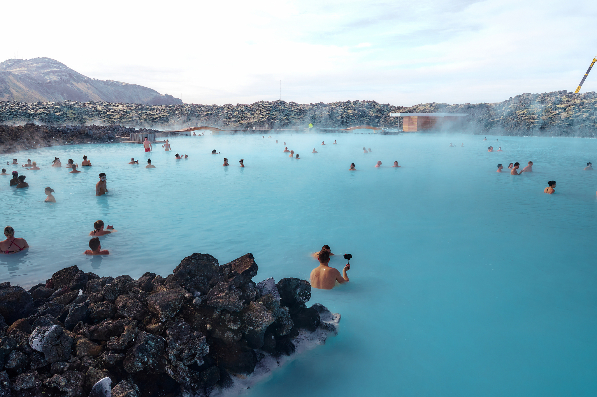 Menschen genießen heiße Quellen in einer blauen Lagune mit Felsen.