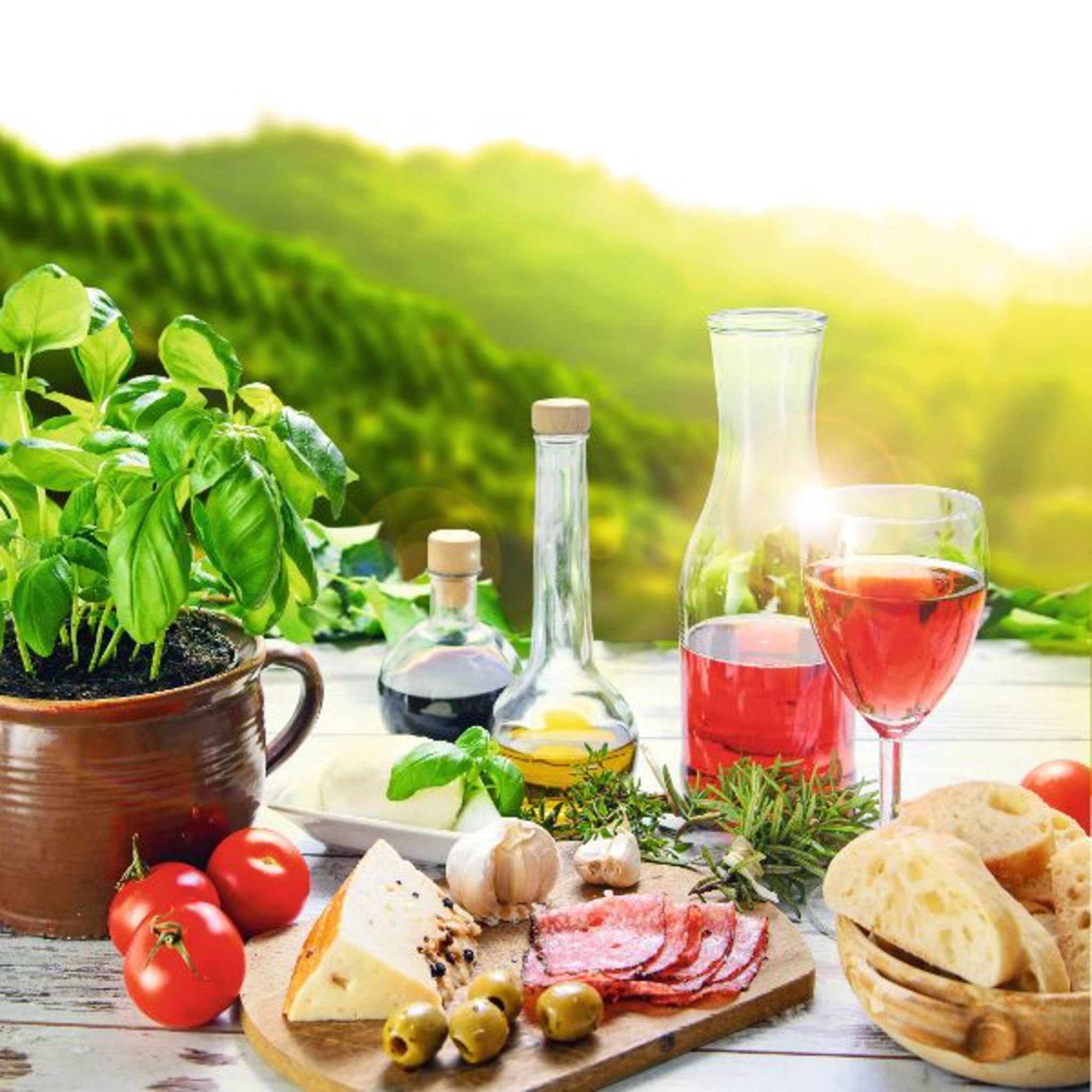 Tisch mit Wurst, Käse, Tomaten, Brot und einem Glas Rotwein in ländlicher Kulisse