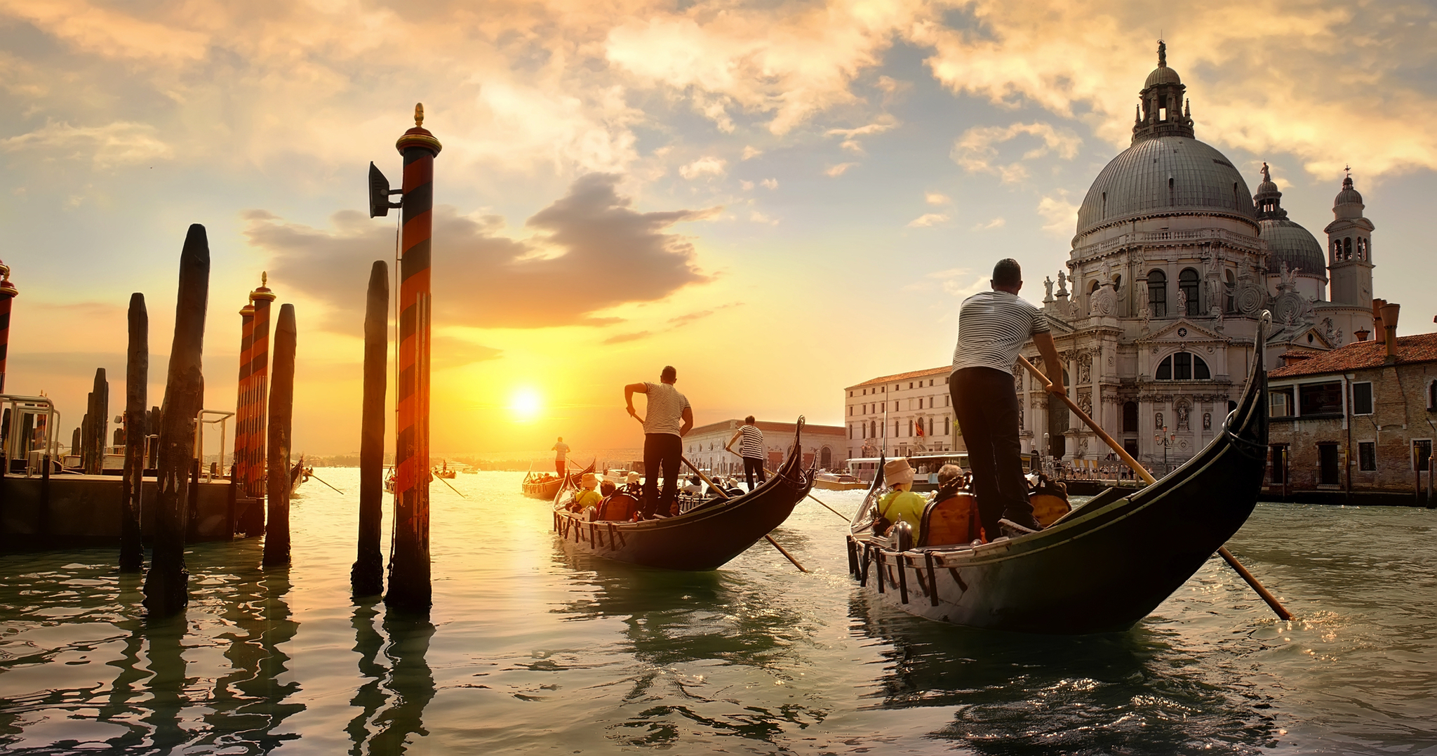 Gondeln fahren bei Sonnenuntergang vor Santa Maria della Salute in Venedig.
