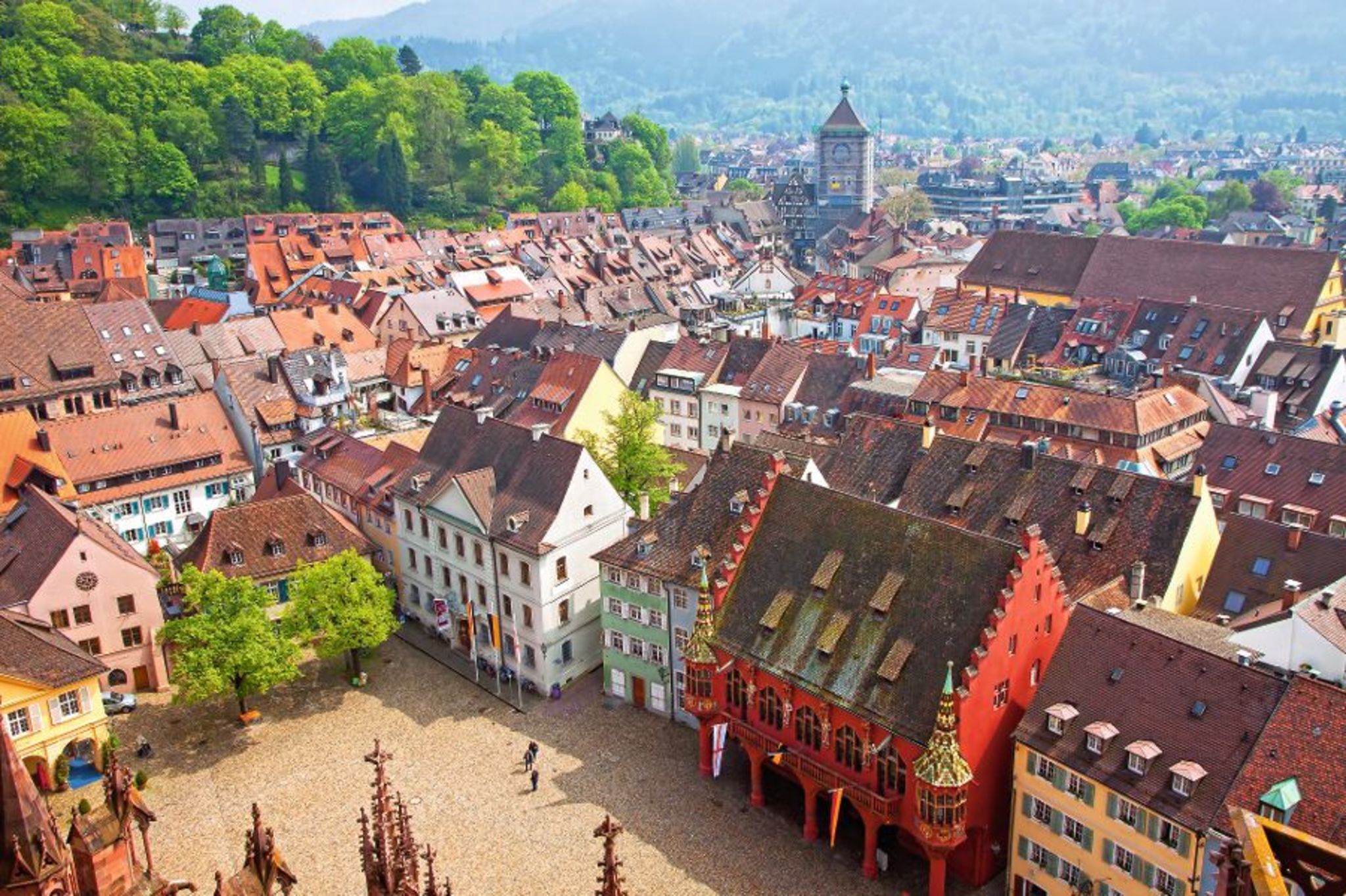 Blick auf malerische Altstadt mit bunten Häusern und gepflastertem Platz im Vordergrund.