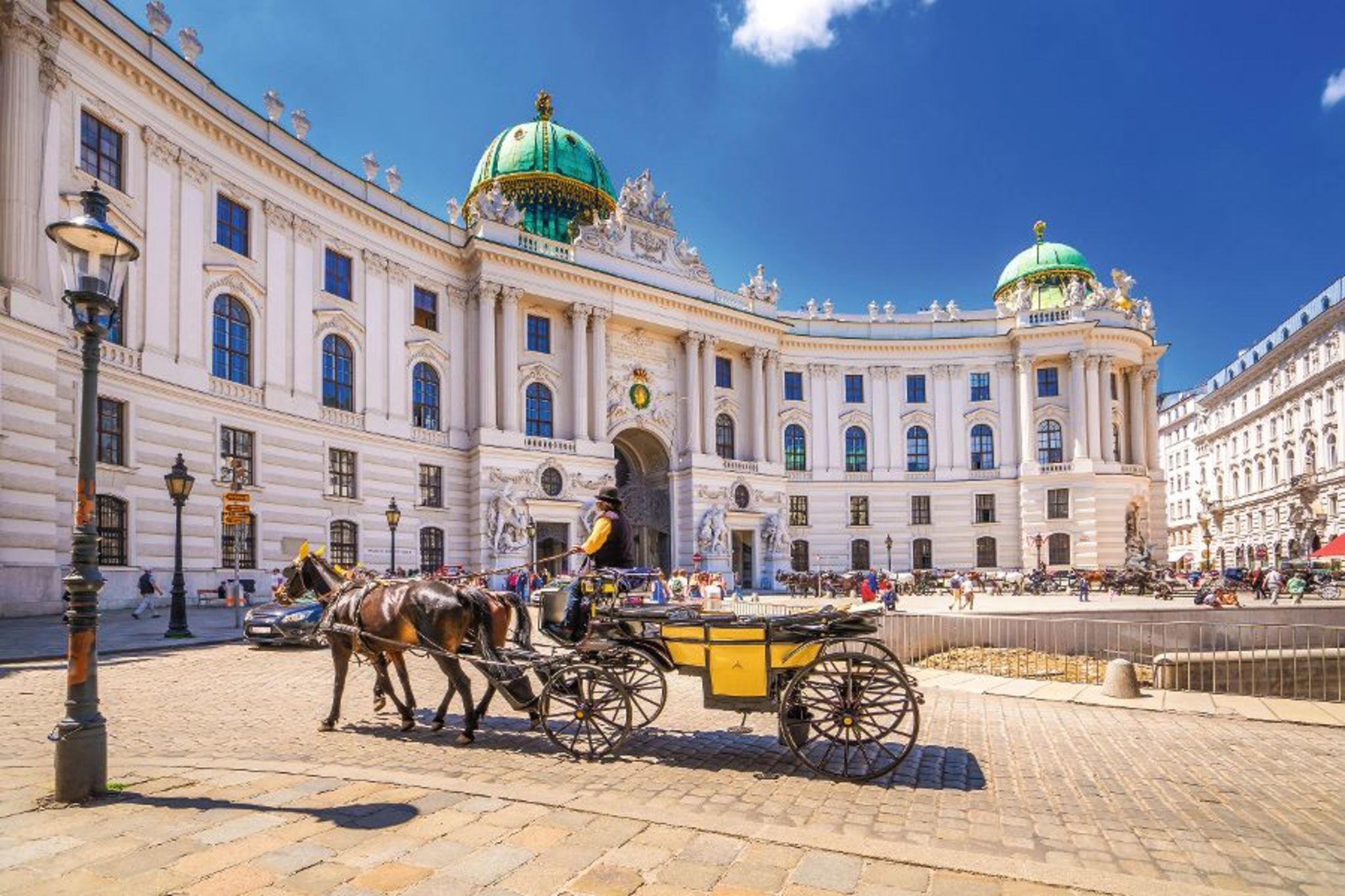 Pferdekutsche vor der Wiener Hofburg an einem sonnigen Tag.