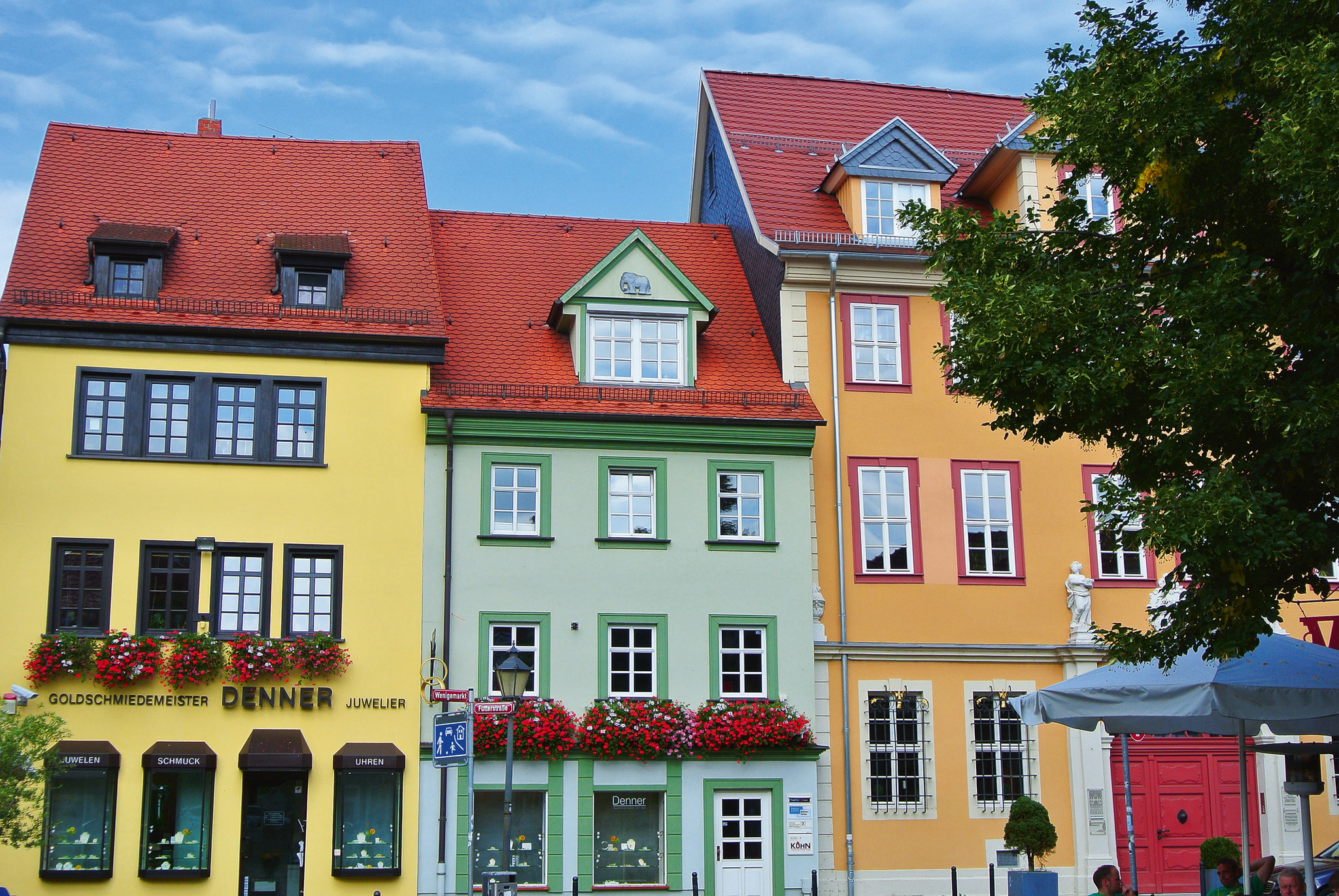 Bunte historische Häuserfassaden in Erfurt, blauer Himmel im Hintergrund.