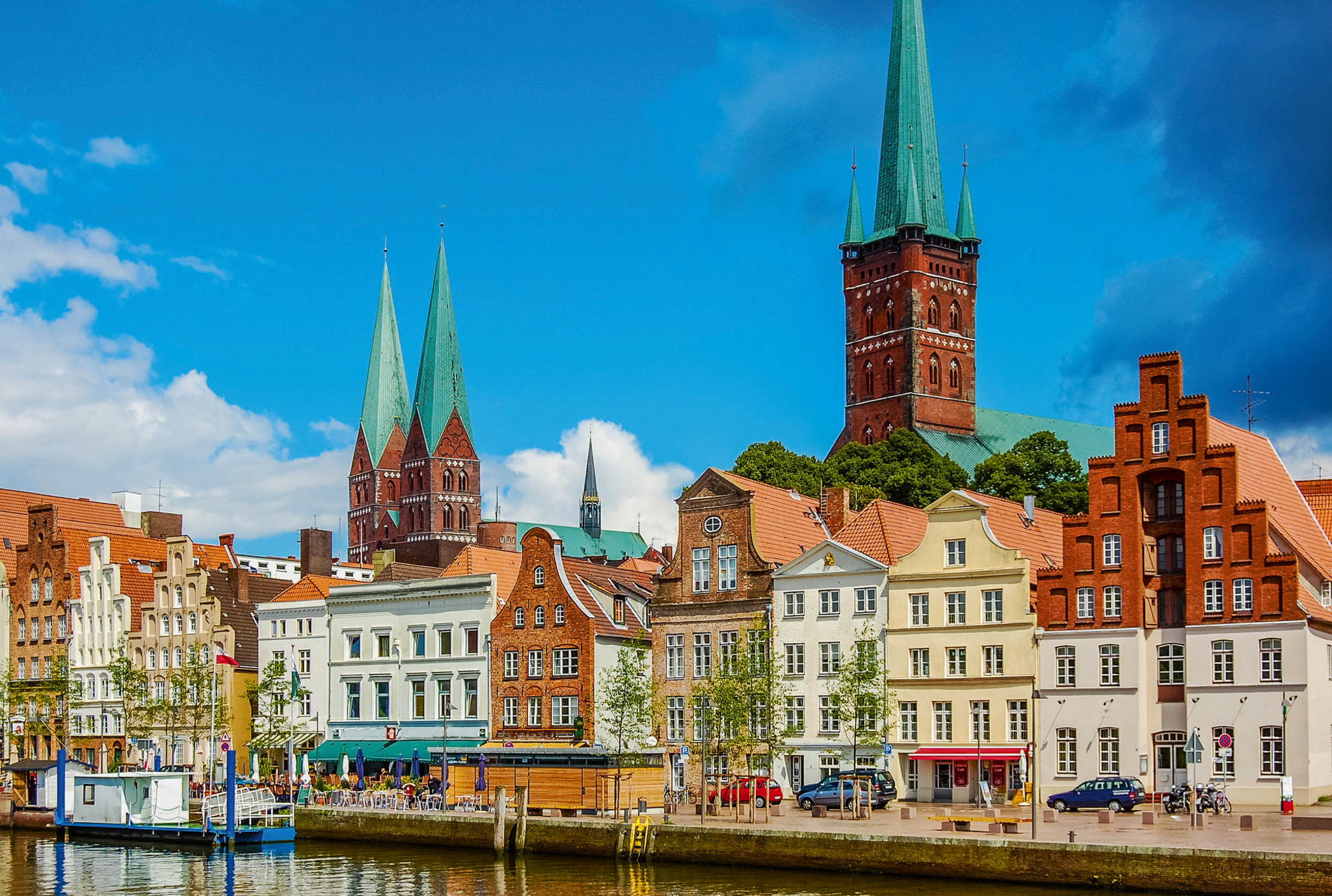 Häuserreihe und Kirchen in Lübeck vor blauem Himmel.