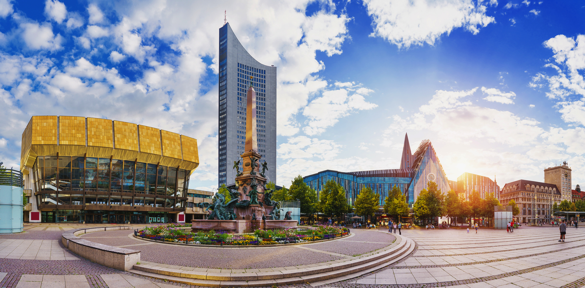 Panorama eines modernen Stadtplatzes mit Wolkenkratzer und Brunnen bei Sonnenschein.
