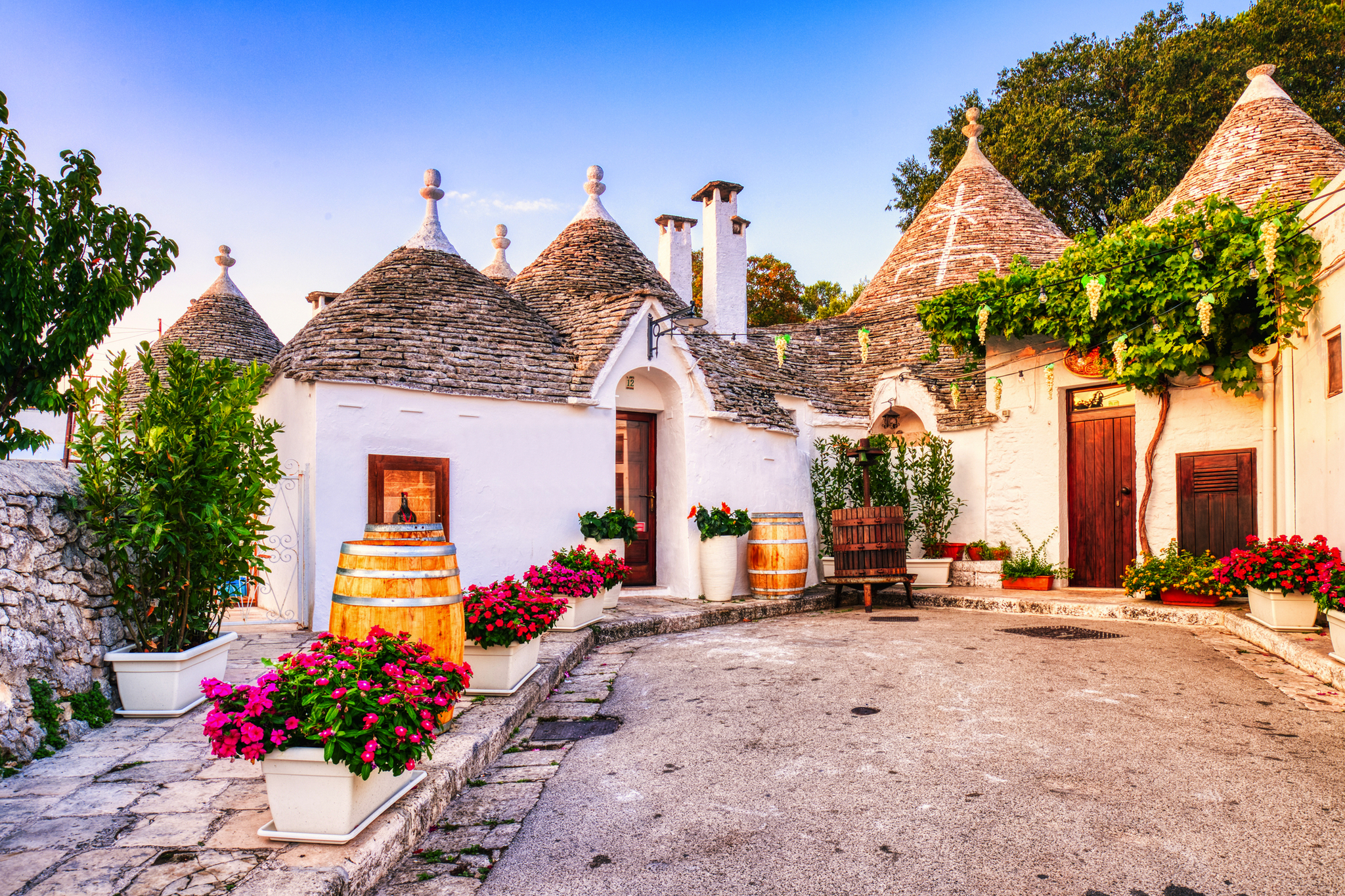 Traditionelle Trulli-Häuser mit Kegeldächern in einer sonnigen italienischen Gasse.