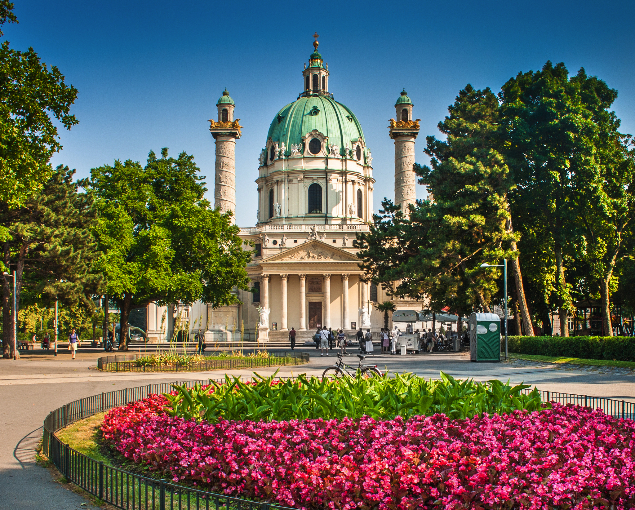 Historische Kirche mit Kuppel und Säulen, umgeben von Park und Blumenbeet.