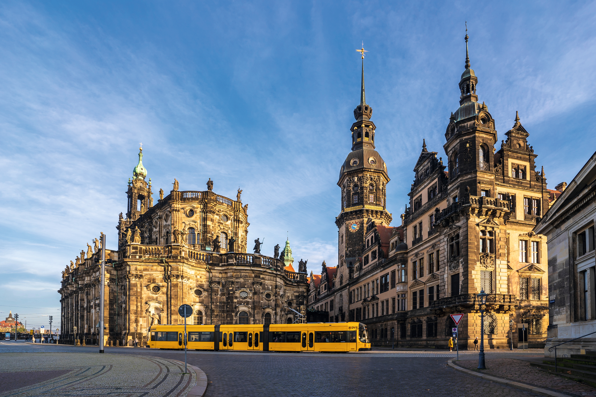 Historische Gebäude und eine Straßenbahn bei sonnigem Wetter in der Stadt Dresden.
