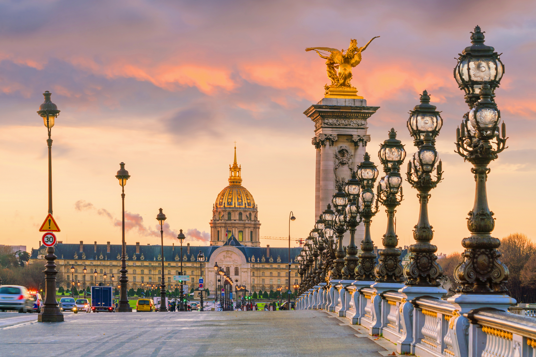 Blick auf die Pont Alexandre III in Paris bei Sonnenuntergang mit Les Invalides im Hintergrund.