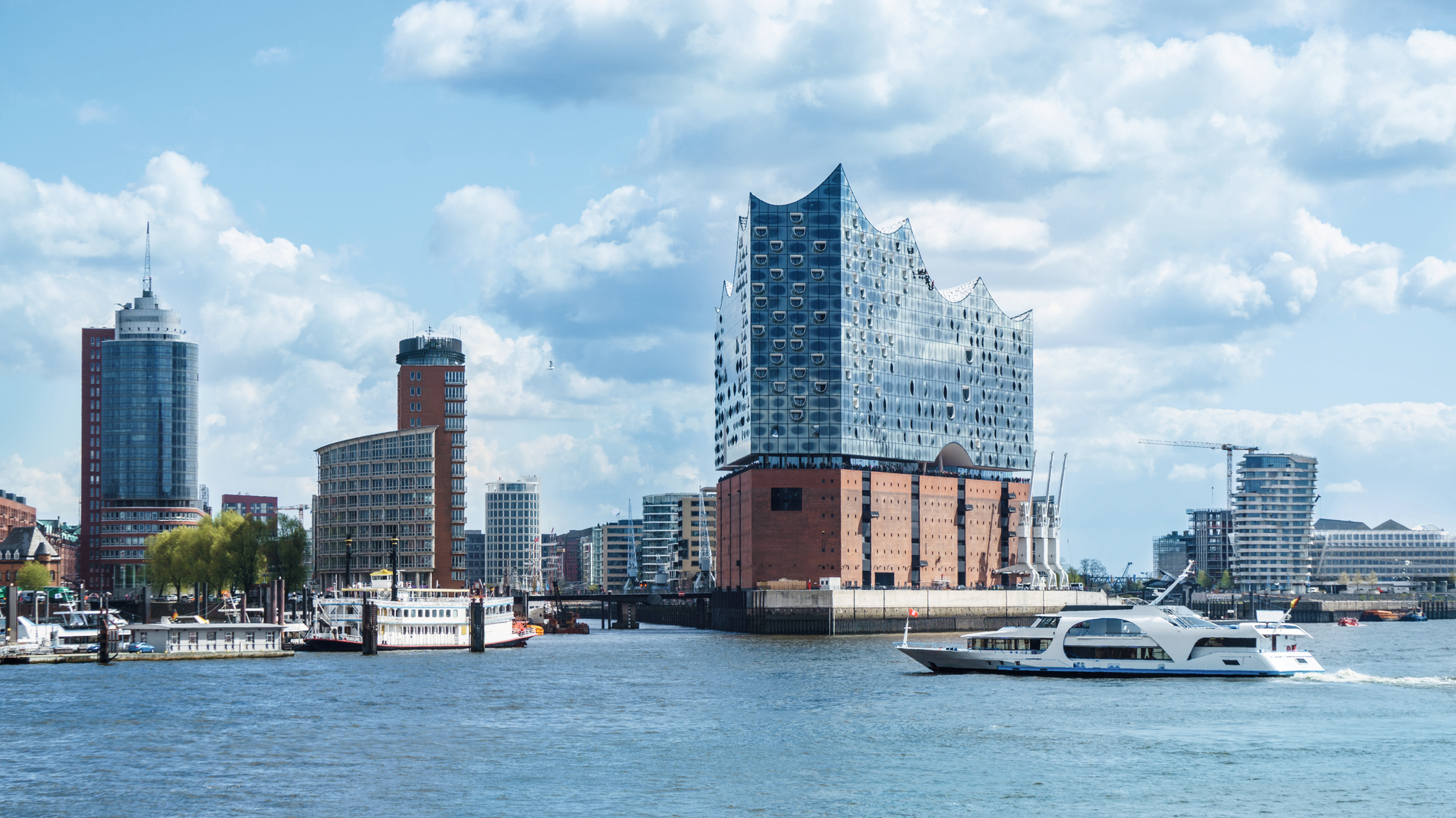 Hamburger Hafen mit Elbphilharmonie, modernen Gebäuden und Booten auf dem Wasser.