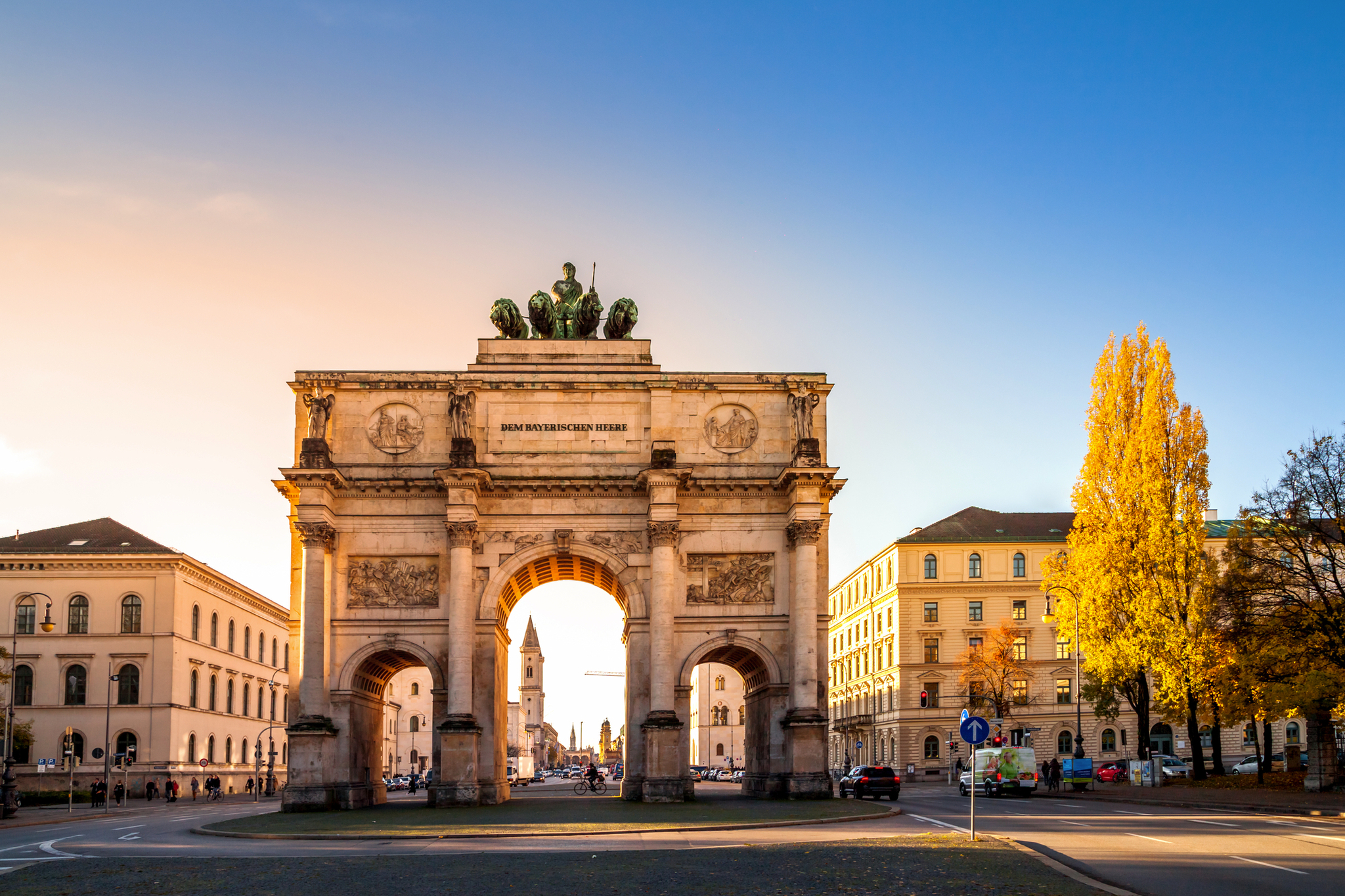Triumphbogen in einer sonnigen Stadtansicht mit Herbstbäumen.