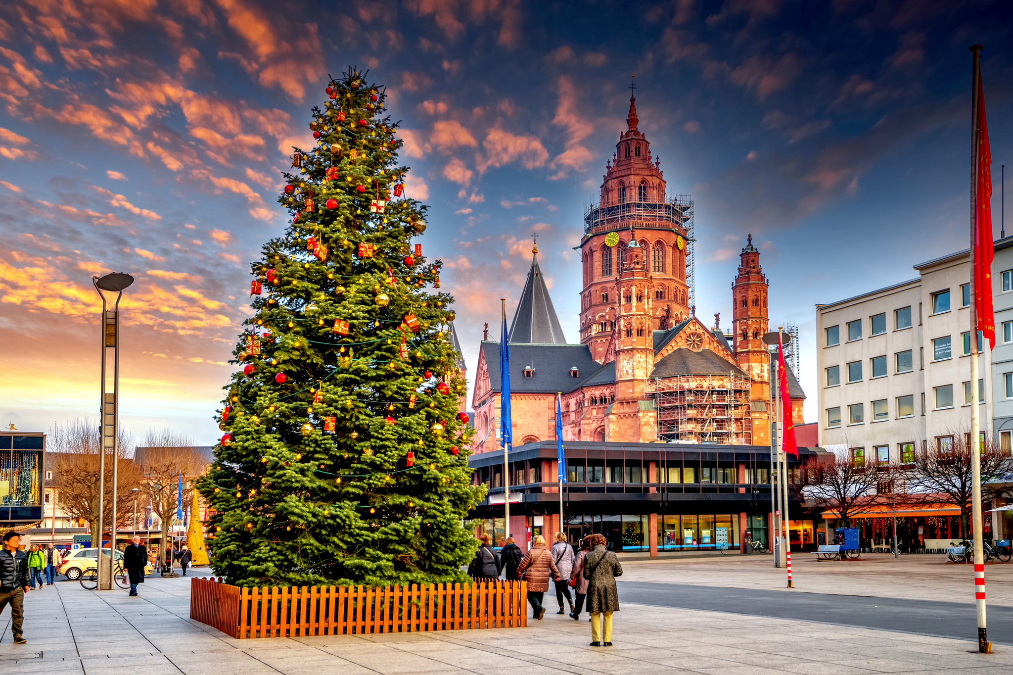 Weihnachtsbaum auf Platz mit Turm und bunter Abendhimmel im Hintergrund