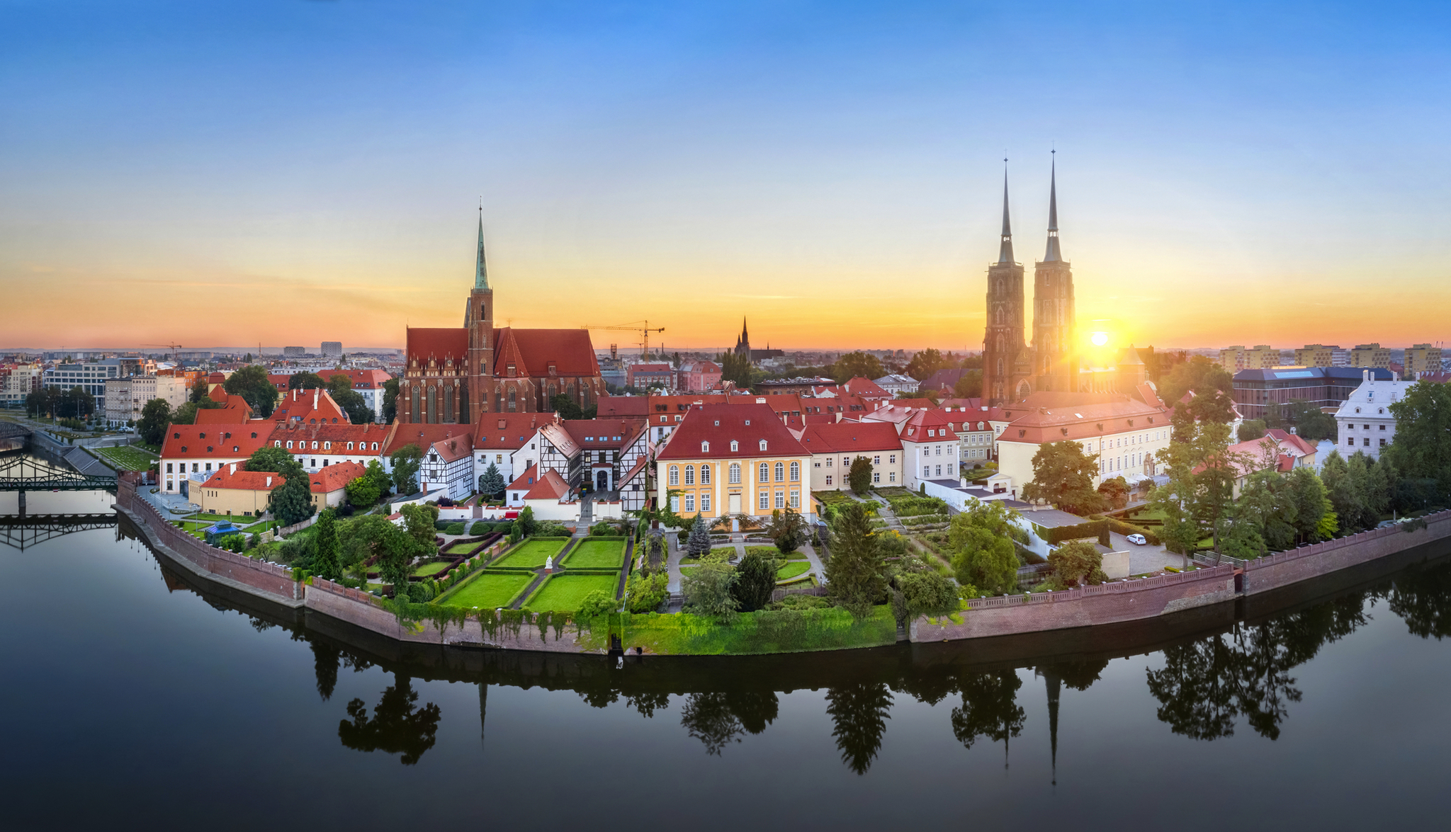 Panorama von Wrocław bei Sonnenuntergang mit Kirche und Fluss.