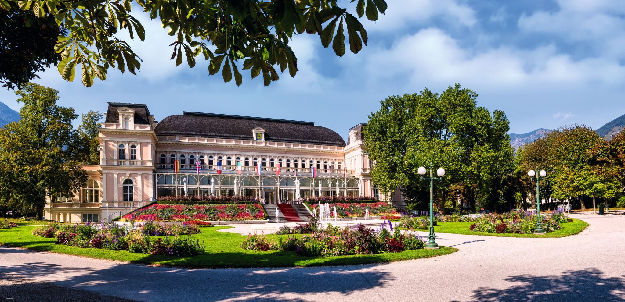 Historisches Gebäude mit Gartenanlage und blühenden Beeten.