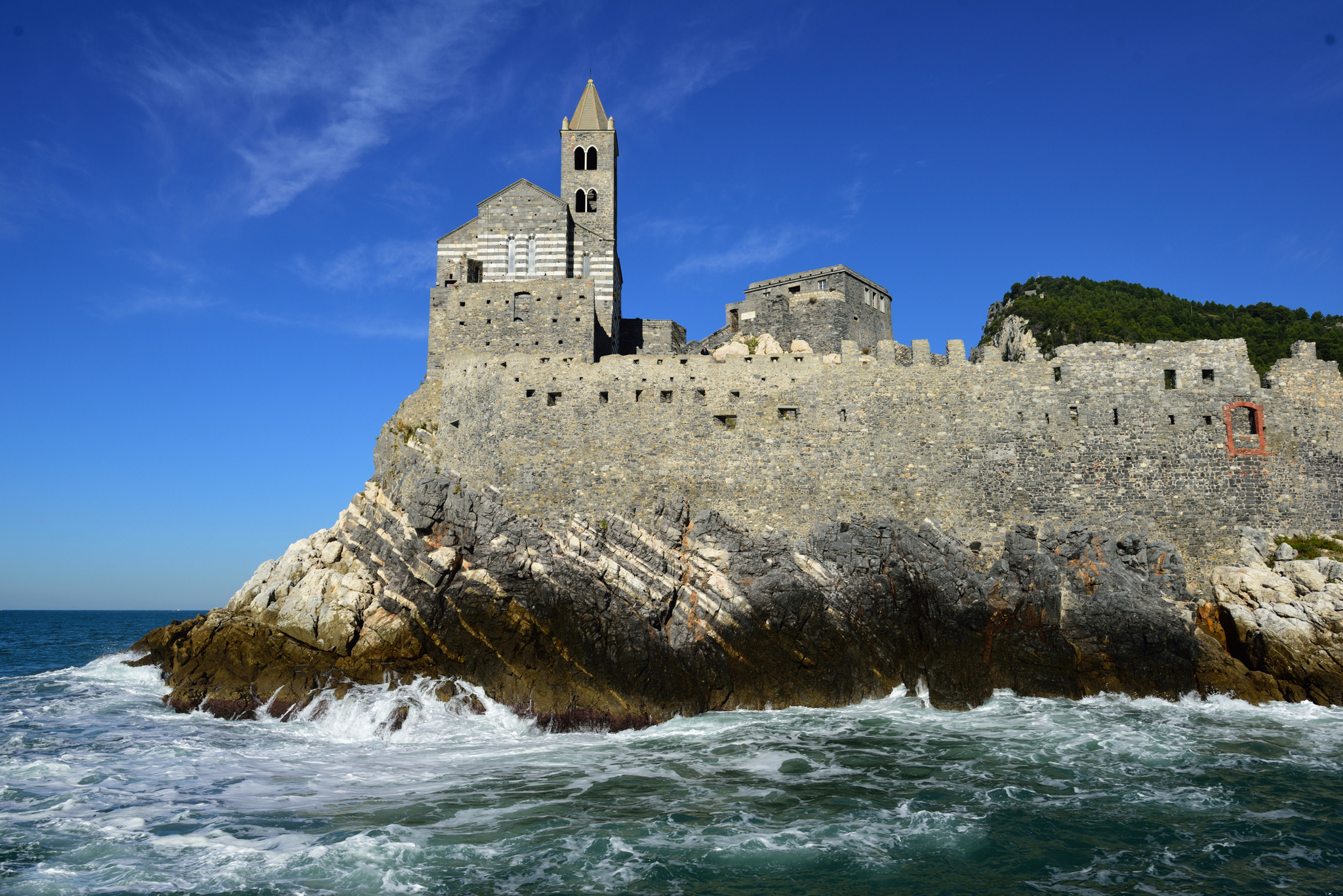 Mittelalterliche Kirche auf Klippe am Meer unter blauem Himmel.
