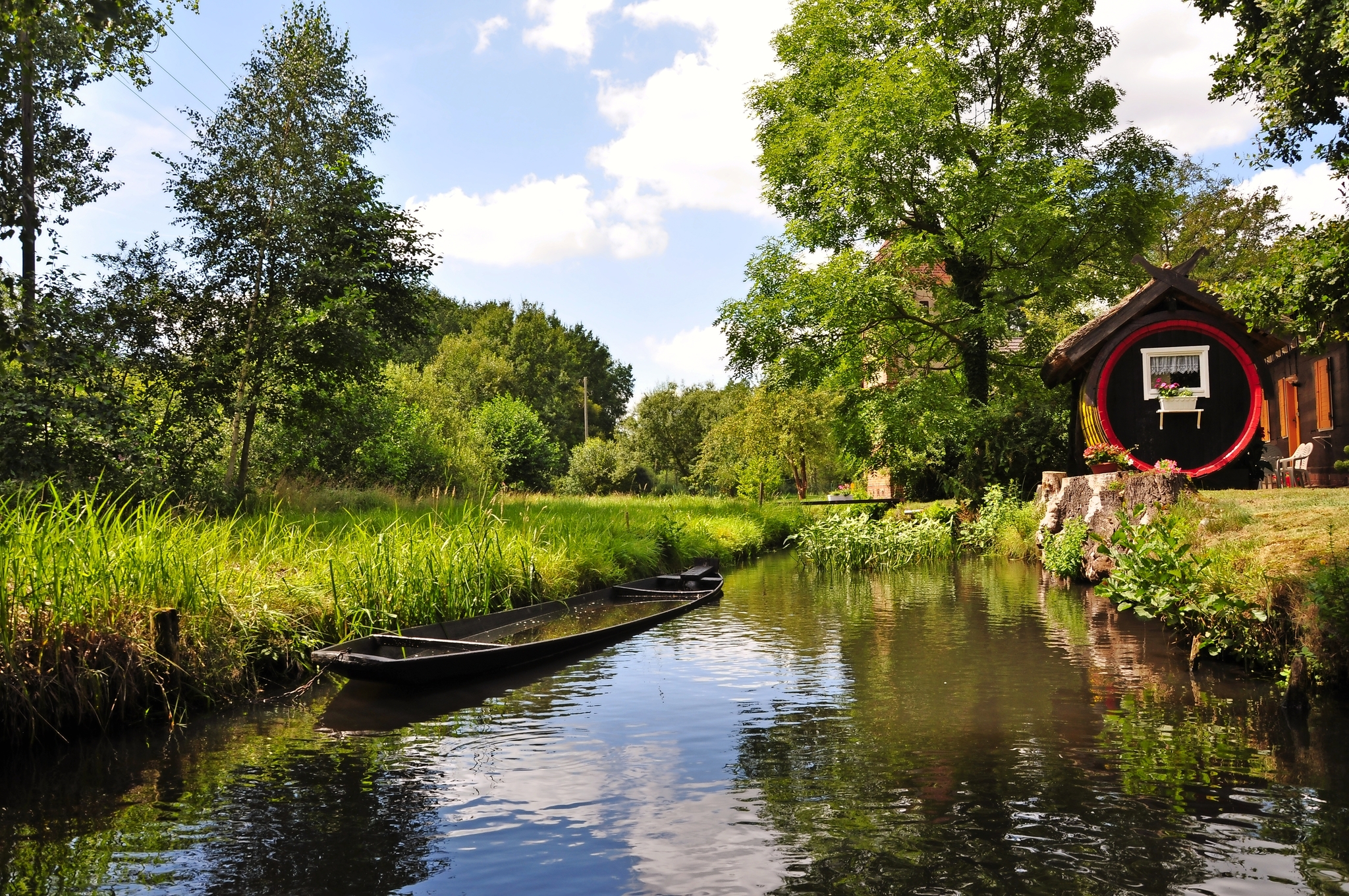 Flusslandschaft mit Kanu und grünen Bäumen unter blauem Himmel.