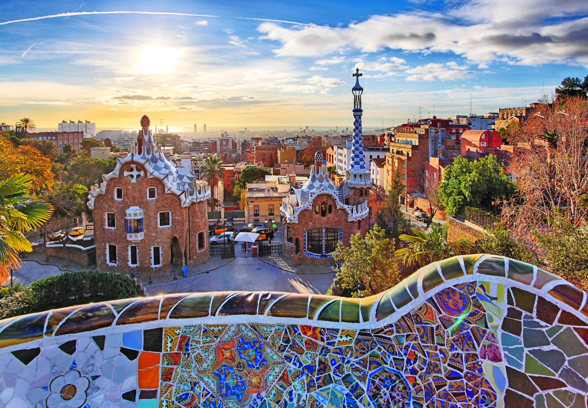 Park Güell in Barcelona mit buntem Mosaik im Vordergrund bei Sonnenuntergang.