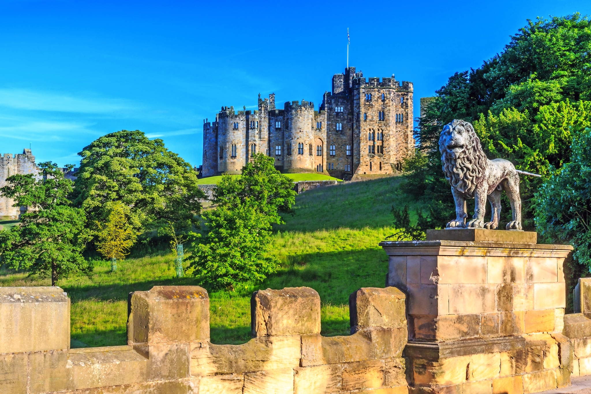 Schloss mit Löwenstatue in einer grünen Landschaft.