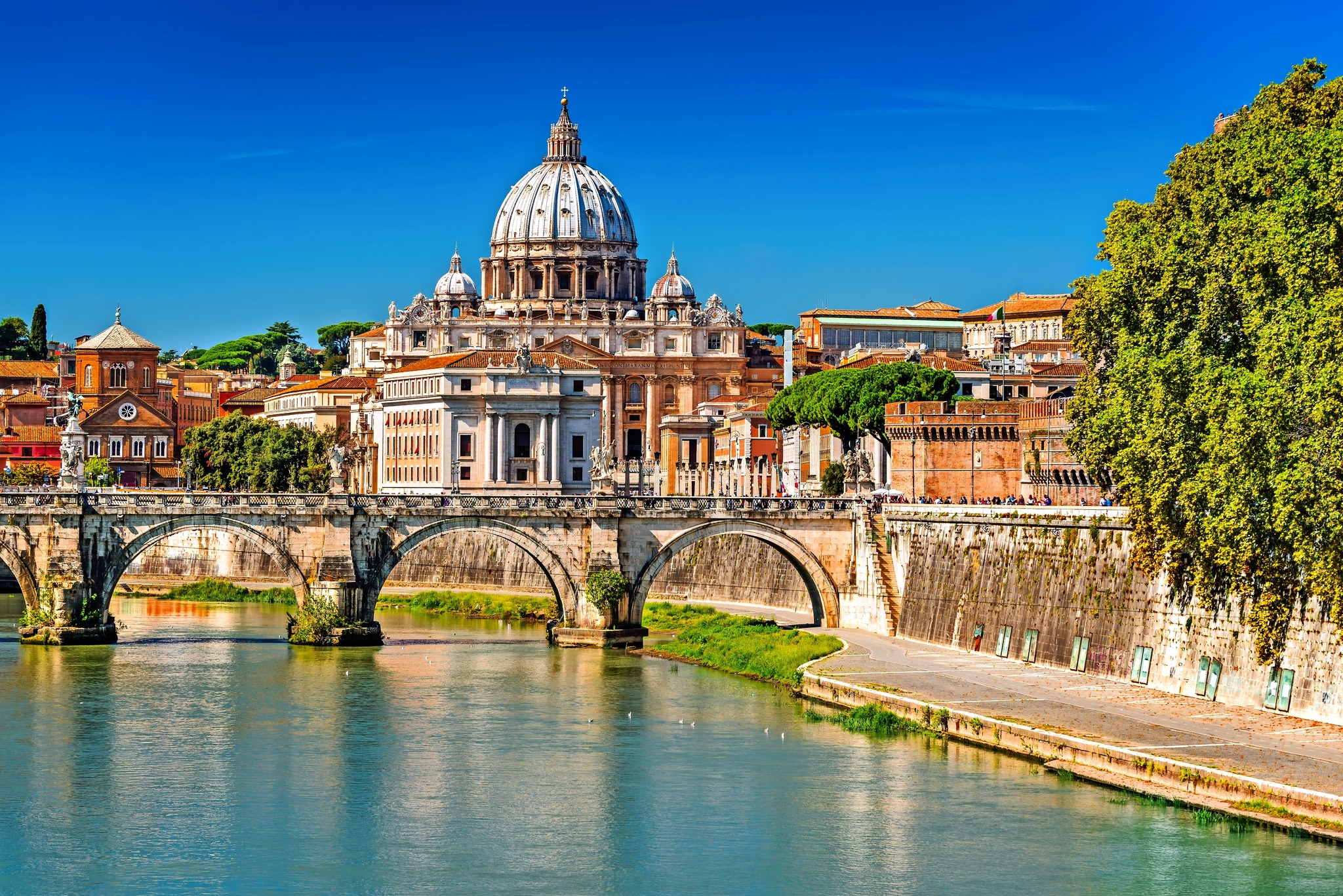 Blick auf den Petersdom in Rom mit der Engelsbrücke und dem Tiber im Vordergrund.