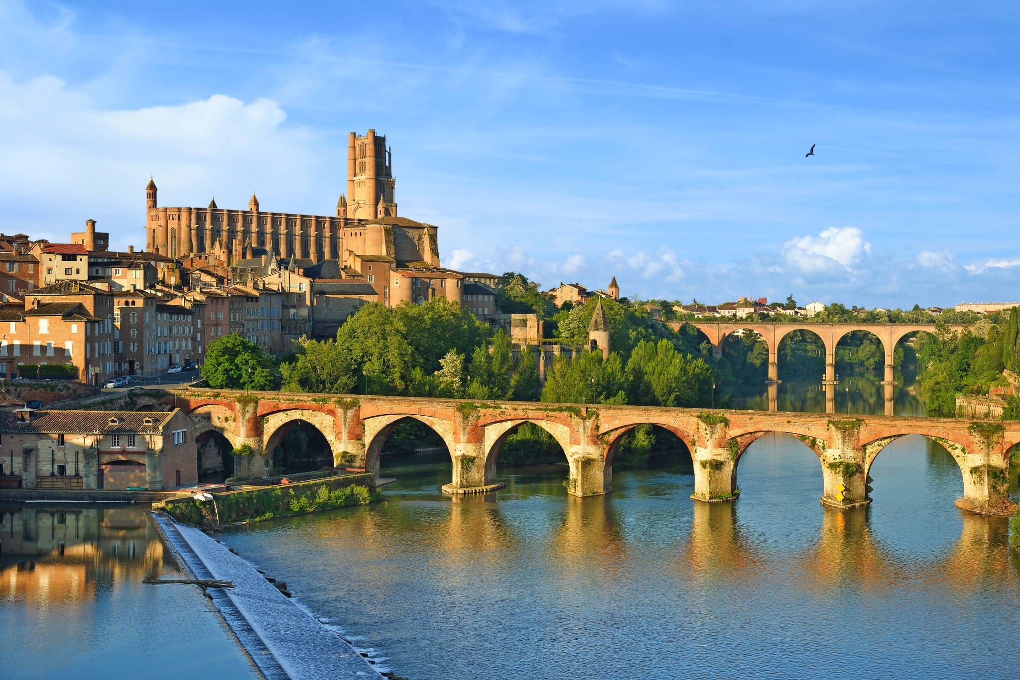 Stadtansicht mit Fluss, historischen Brücken und einer großen Kathedrale im Hintergrund.