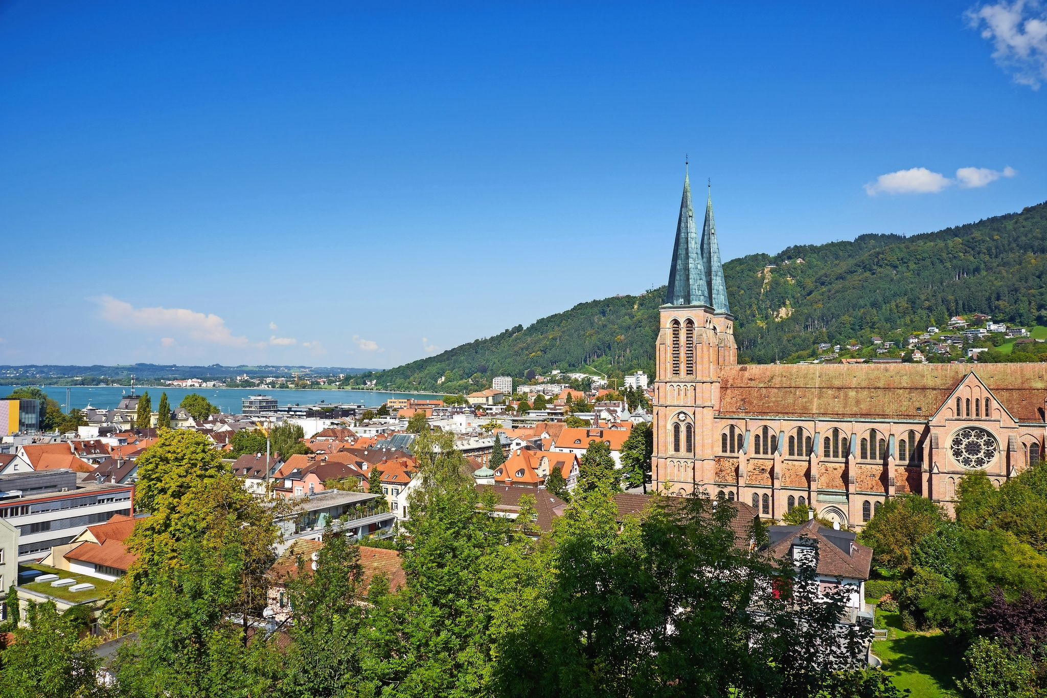 Stadtansicht mit Kirche, blauer Himmel und Hügel im Hintergrund.
