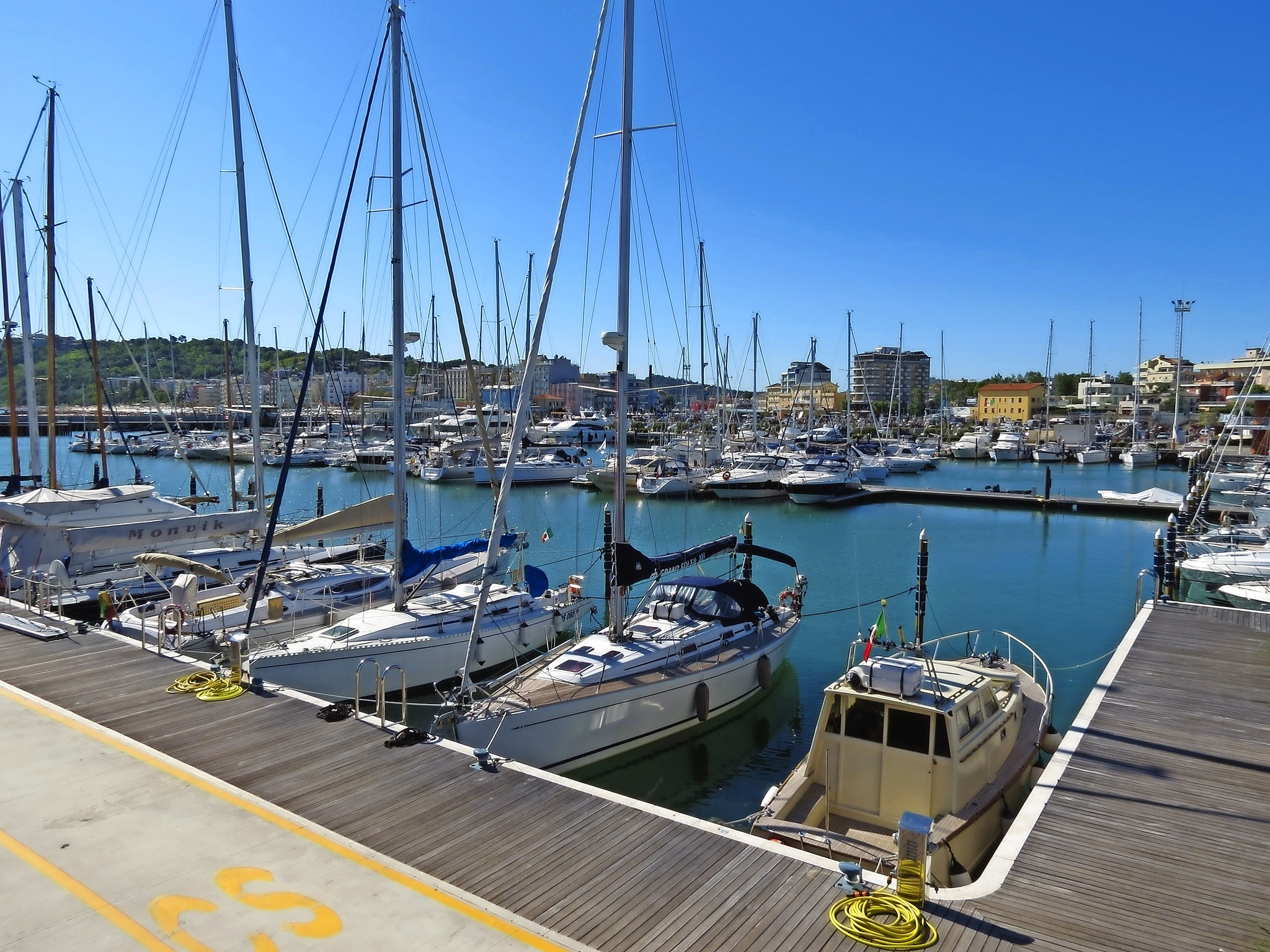 Segelboote und Yachten, die in einem Hafen anlegen, mit strahlend blauem Himmel im Hintergrund.