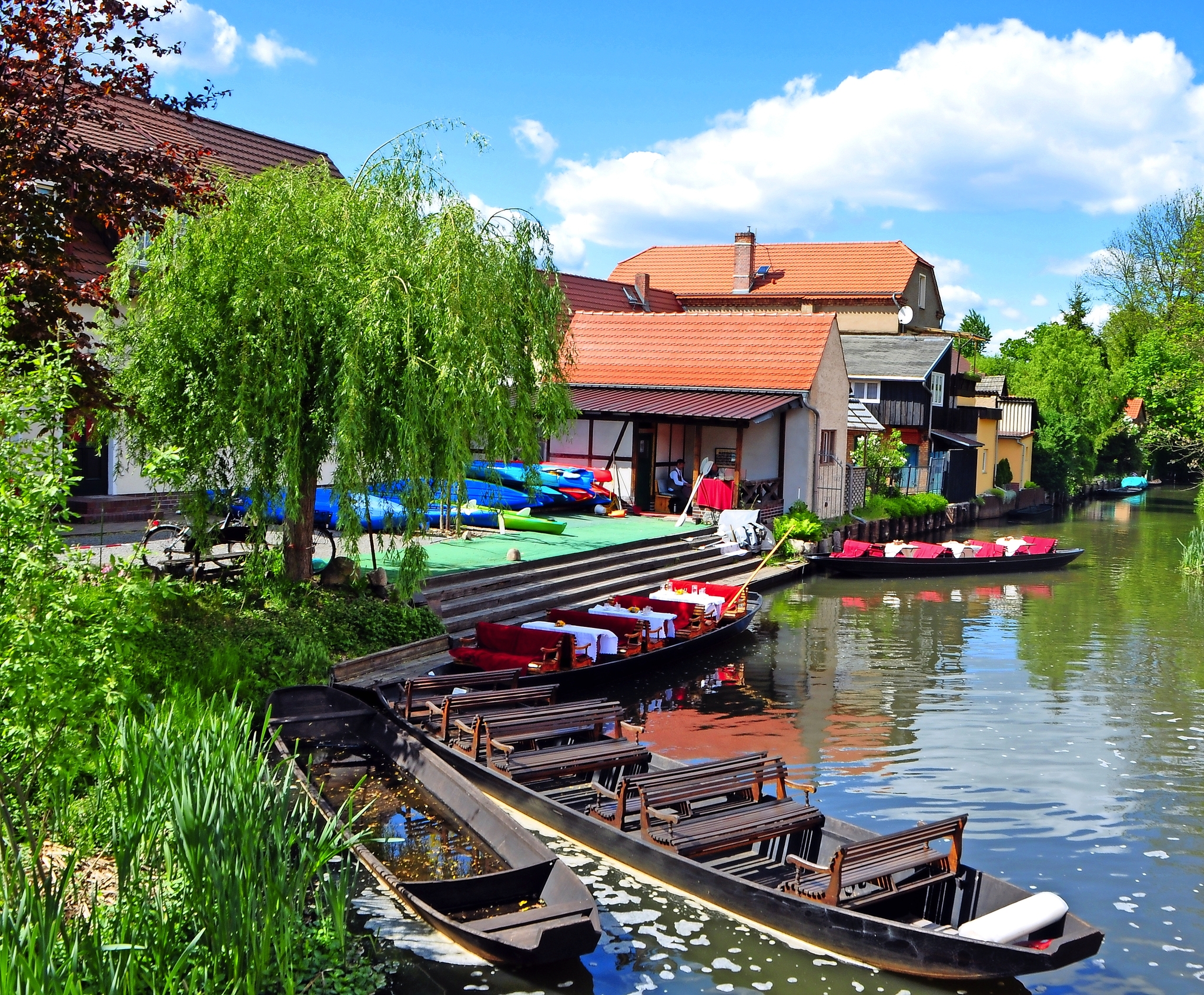 Häuser und Boote am Flussufer bei sonnigem Wetter.