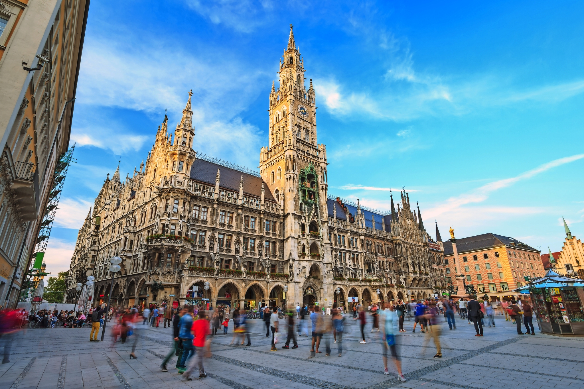 Marienplatz mit dem Neuen Rathaus in München, Menschenmenge und blauer Himmel.