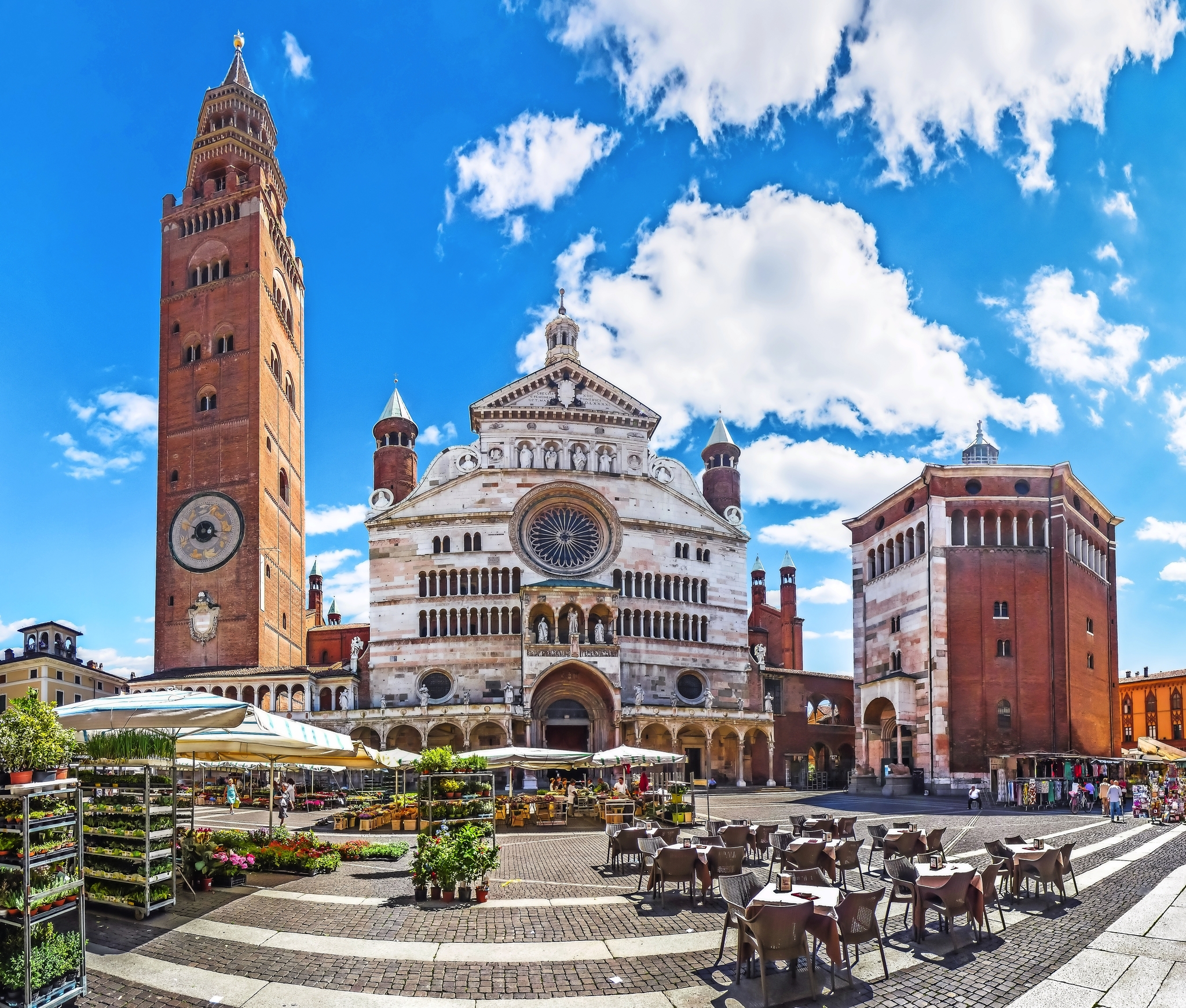 Historischer Domplatz mit Kathedrale und Turm bei blauem Himmel und Marktständen.