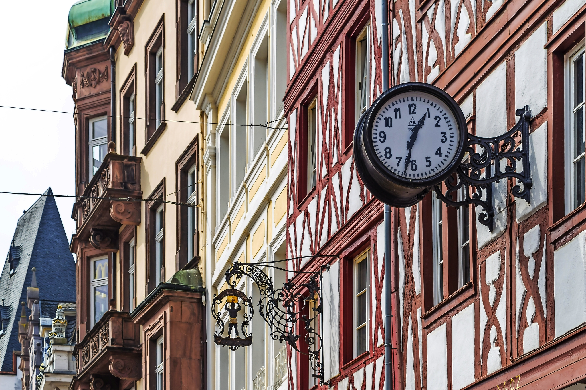 Fachwerkhäuser mit einer analogen Wanduhr in einer Altstadt.