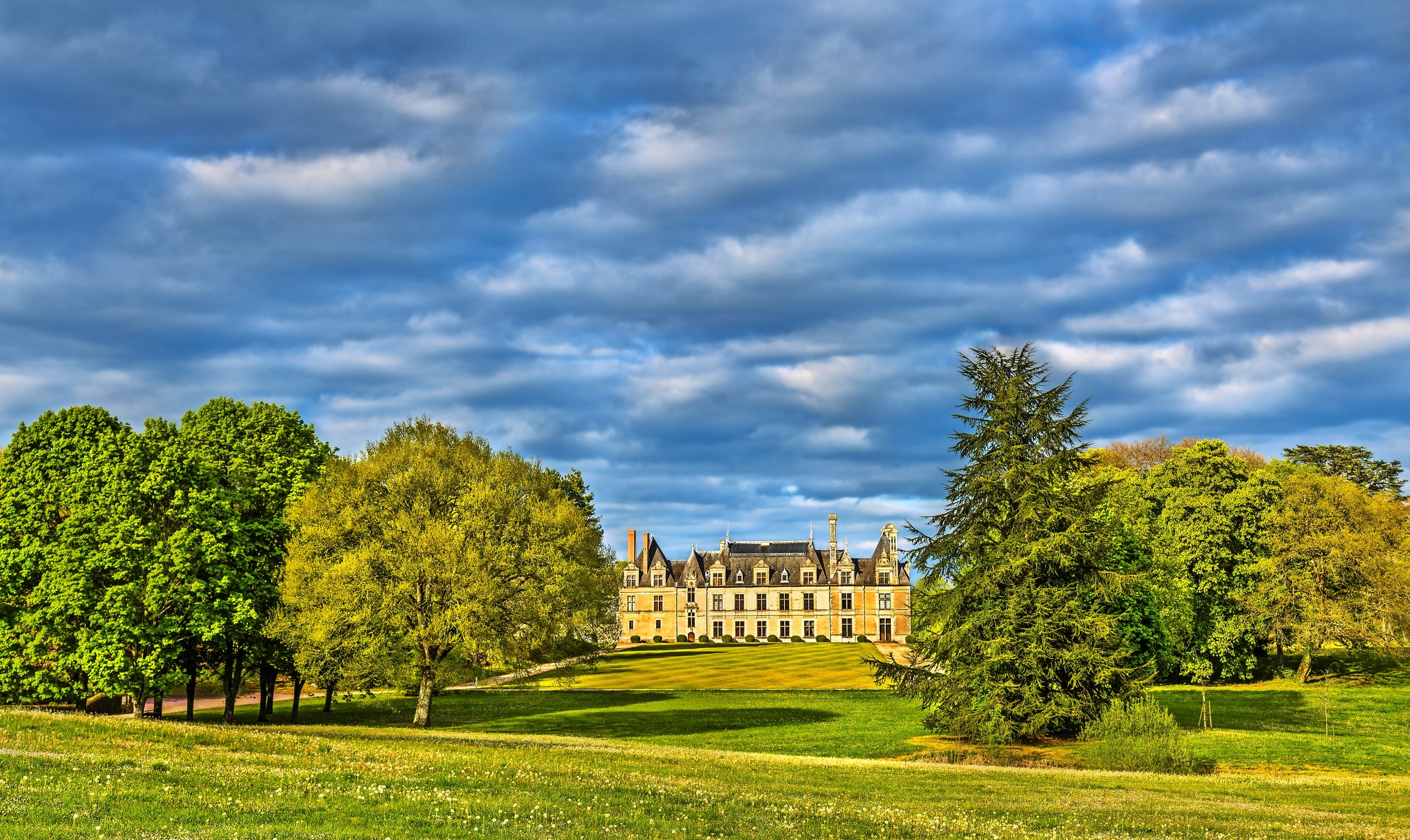 Schloss inmitten von grünen Bäumen und Wolkenhimmel im Hintergrund