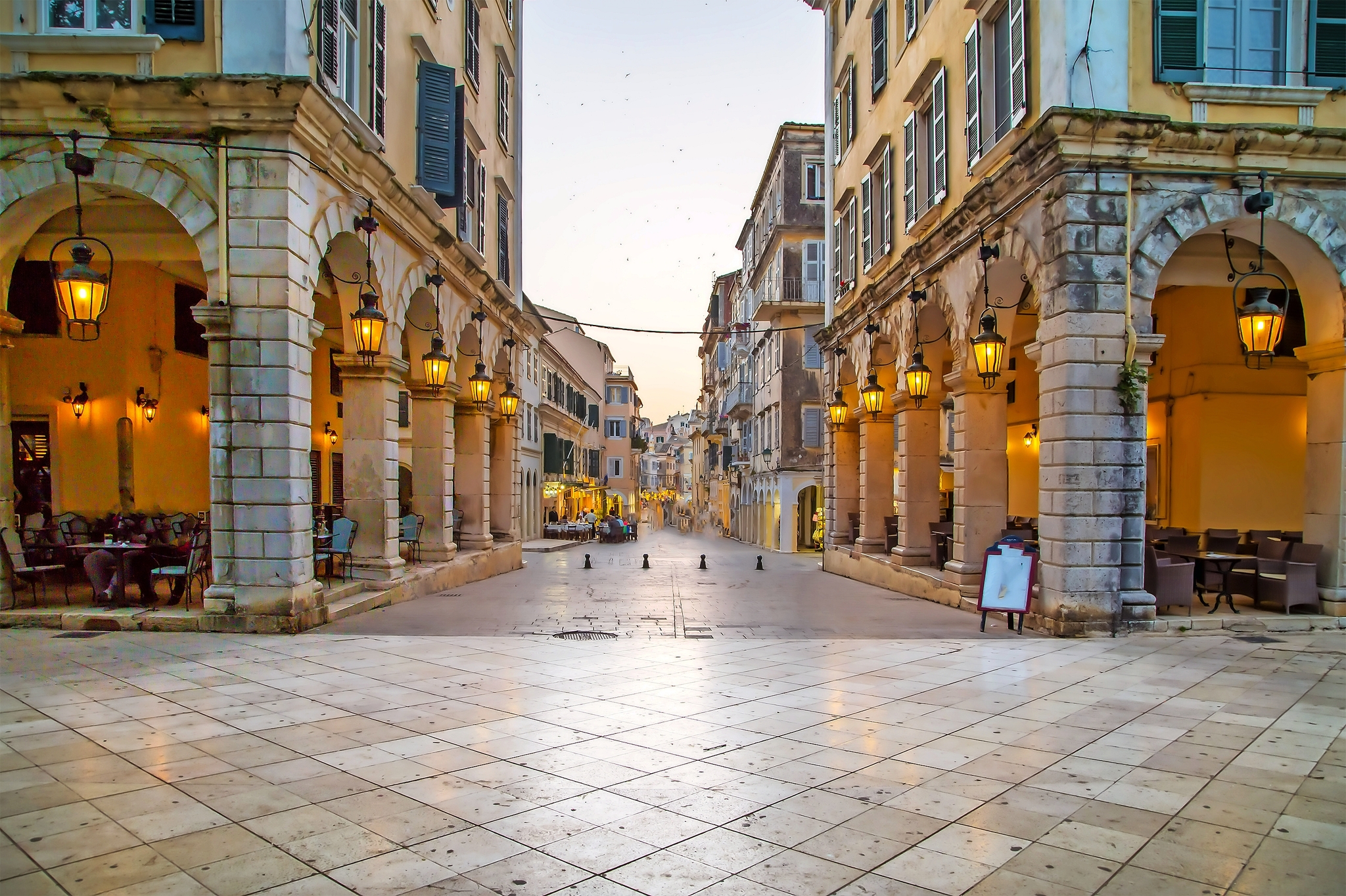 Historische Gasse mit Arkaden und Laternen in einer europäischen Stadt.
