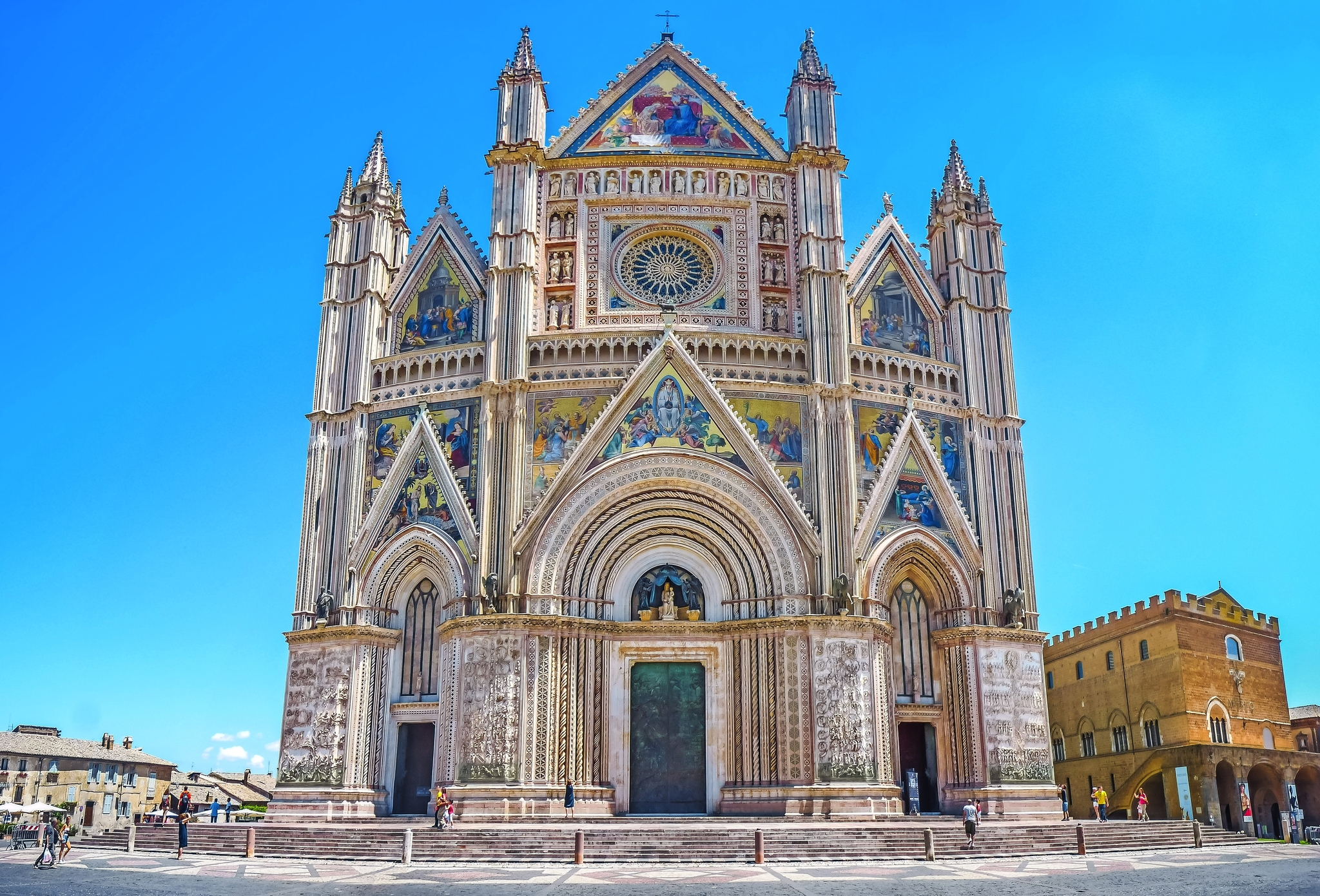 Gotische Kathedrale mit reich verzierten Fassaden und blauen Himmel im Hintergrund.