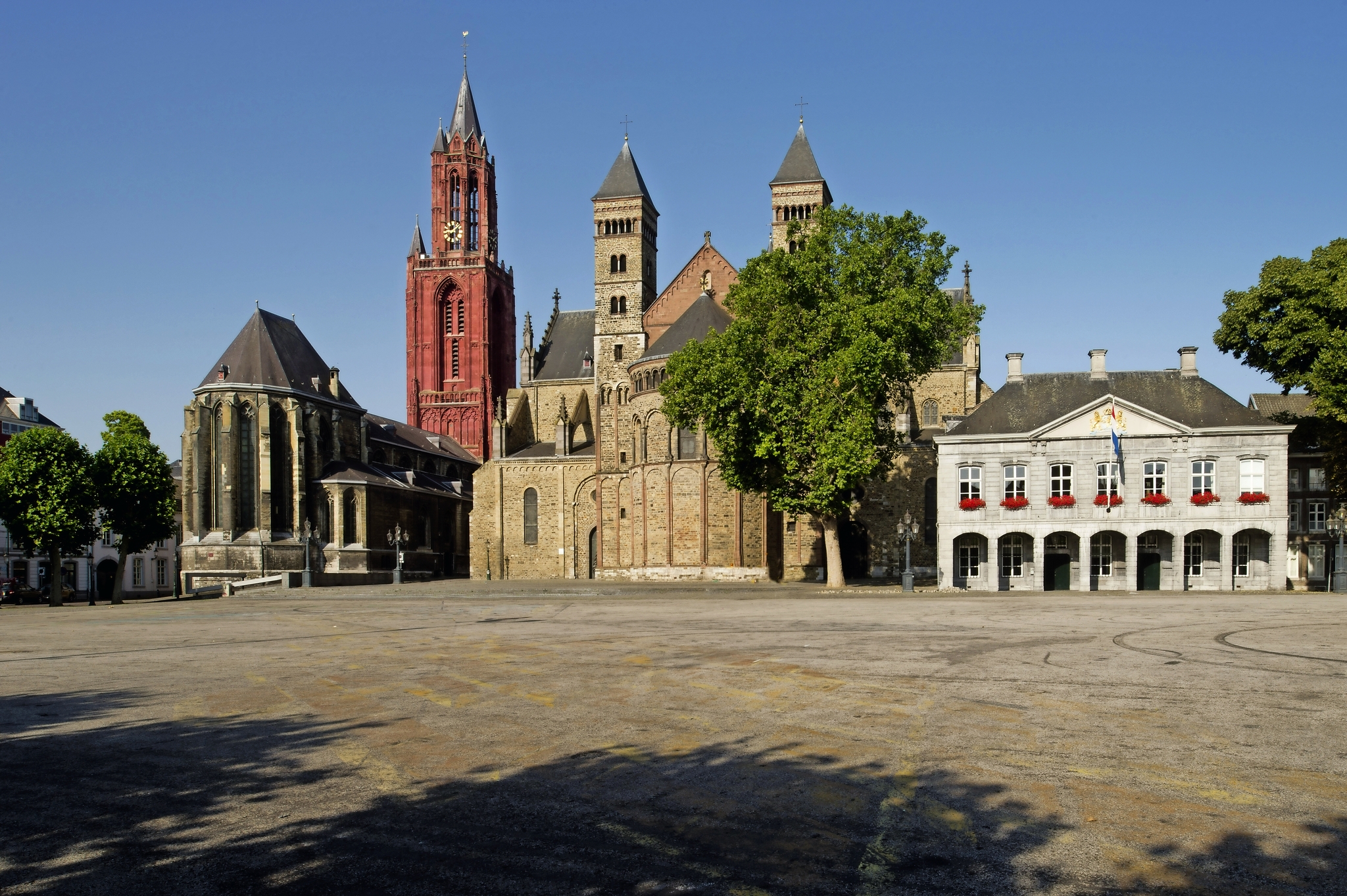 Historische Kirche und Gebäude an einem leeren Platz bei klarem Himmel.
