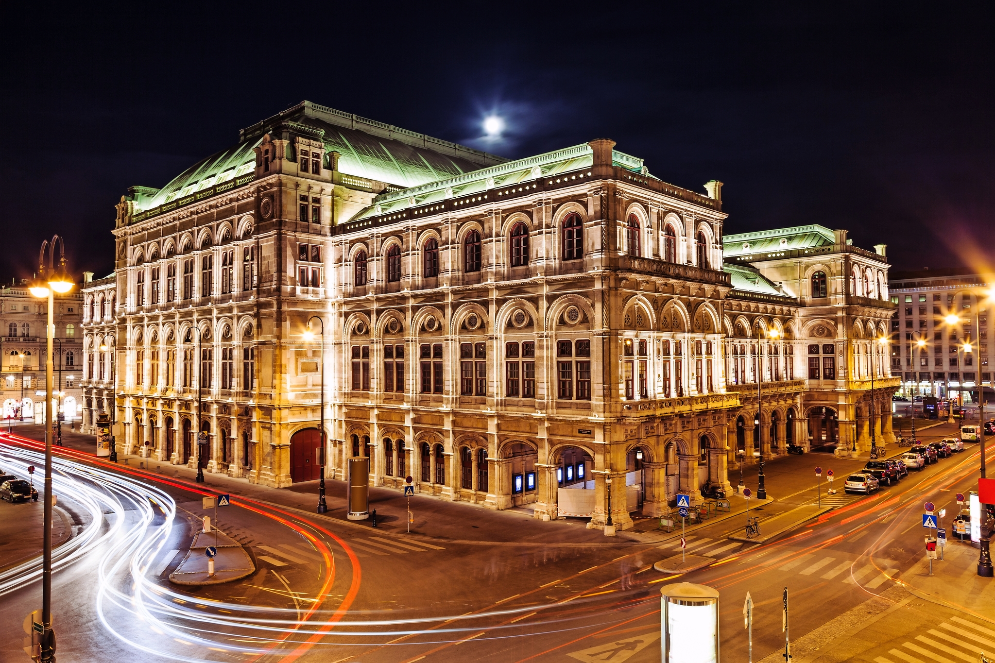 Historisches Operngebäude bei Nacht mit beleuchteten Fassaden.