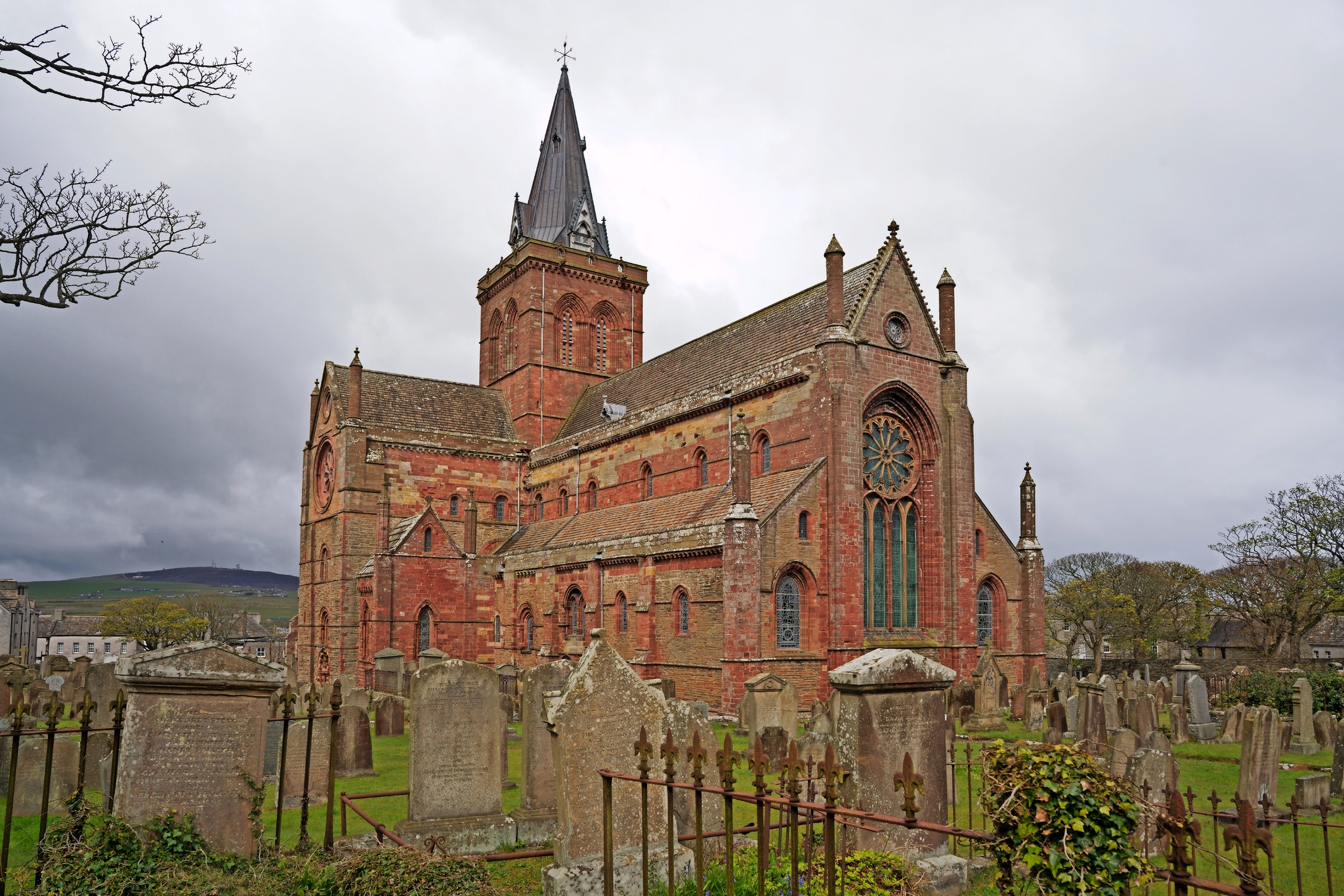Alte Backsteinkirche mit Friedhof und bewölktem Himmel.