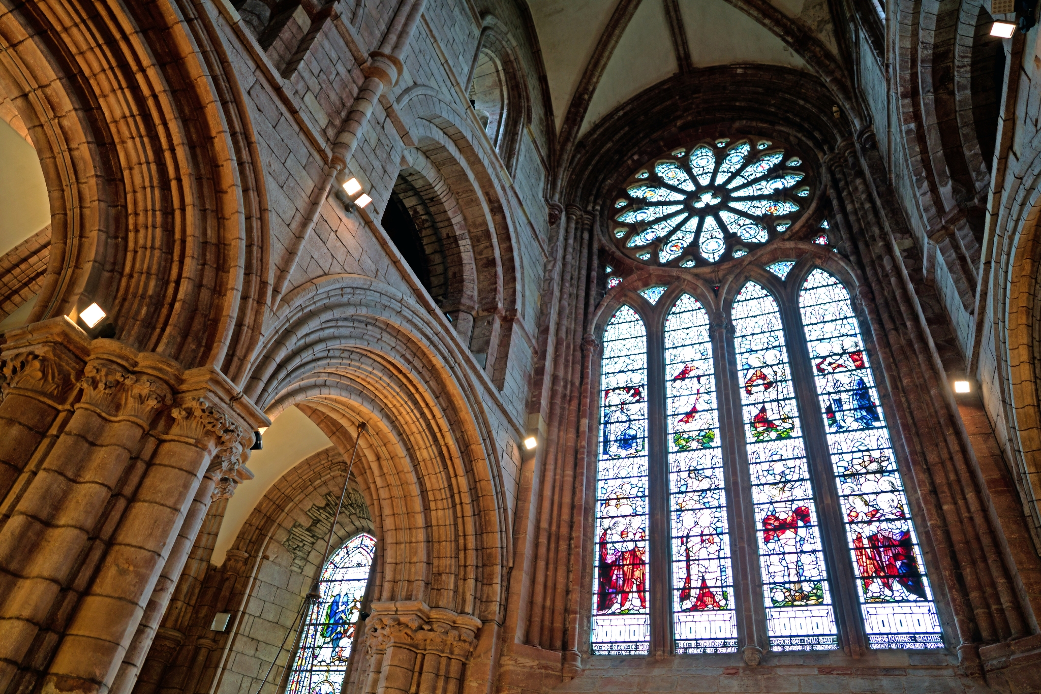 Gotische Kirchenfenster und Bögen aus Stein im Innenraum einer Kathedrale.