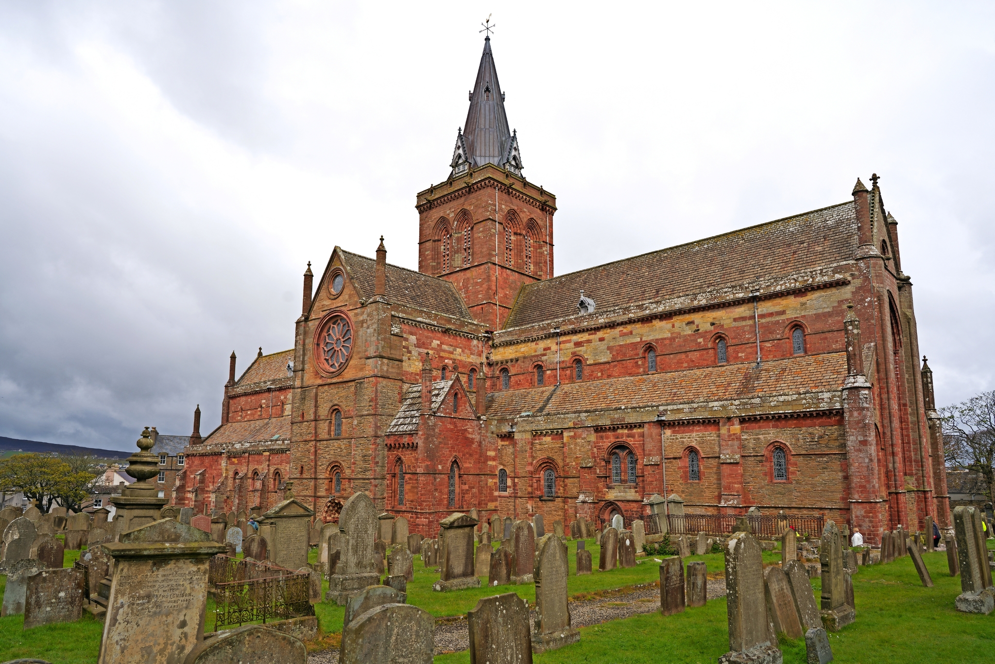 Backsteinkirche mit Kirchturm auf einem Friedhof.