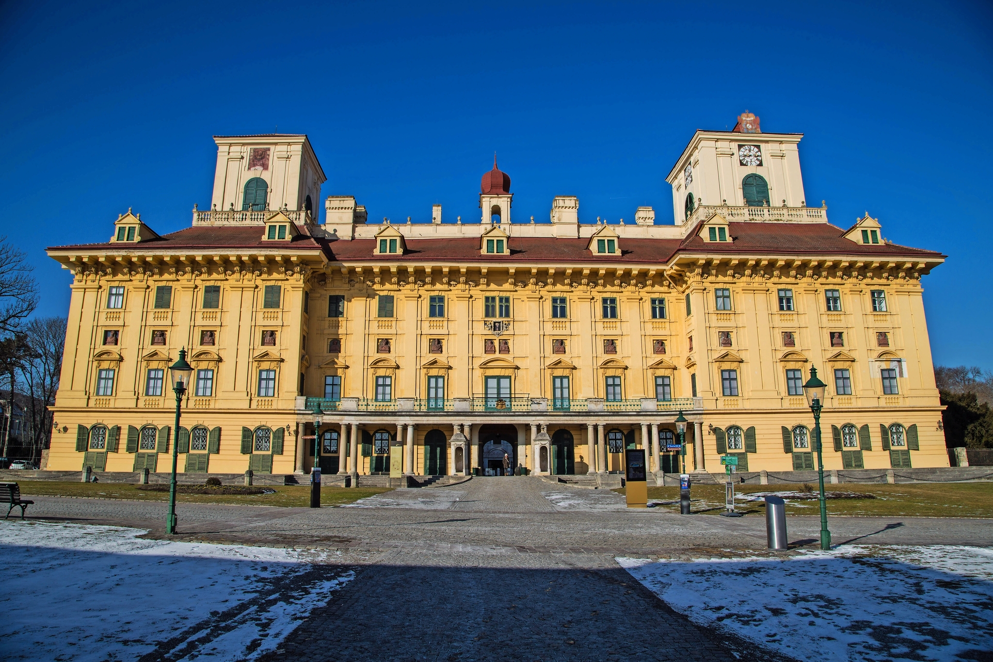 Großes gelbes Barockschloss an einem klaren Tag mit blauem Himmel.