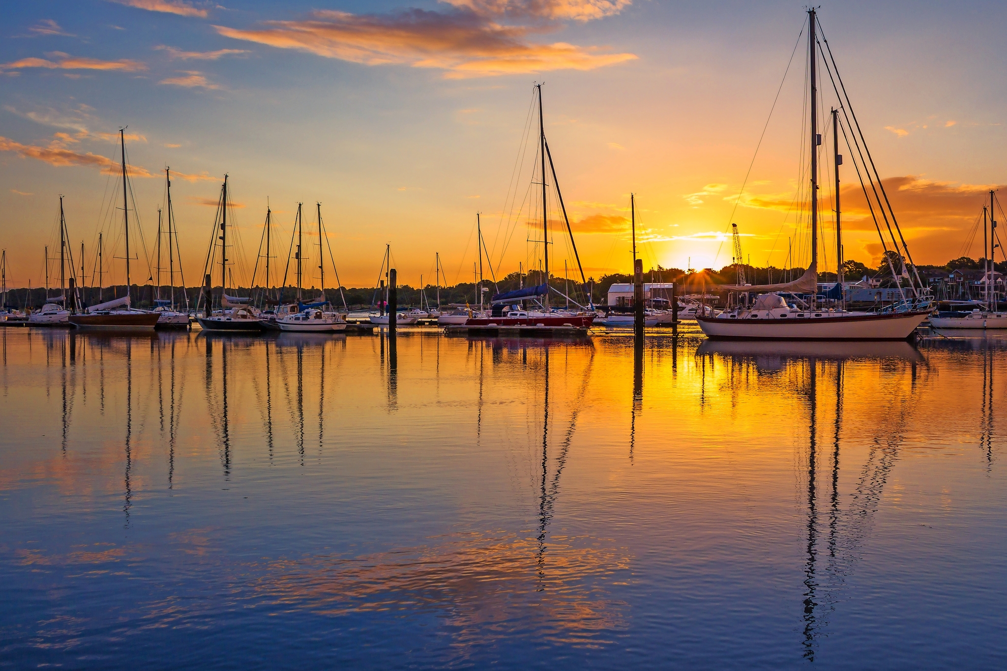 Segelboote im Hafen bei Sonnenuntergang mit Spiegelung im Wasser