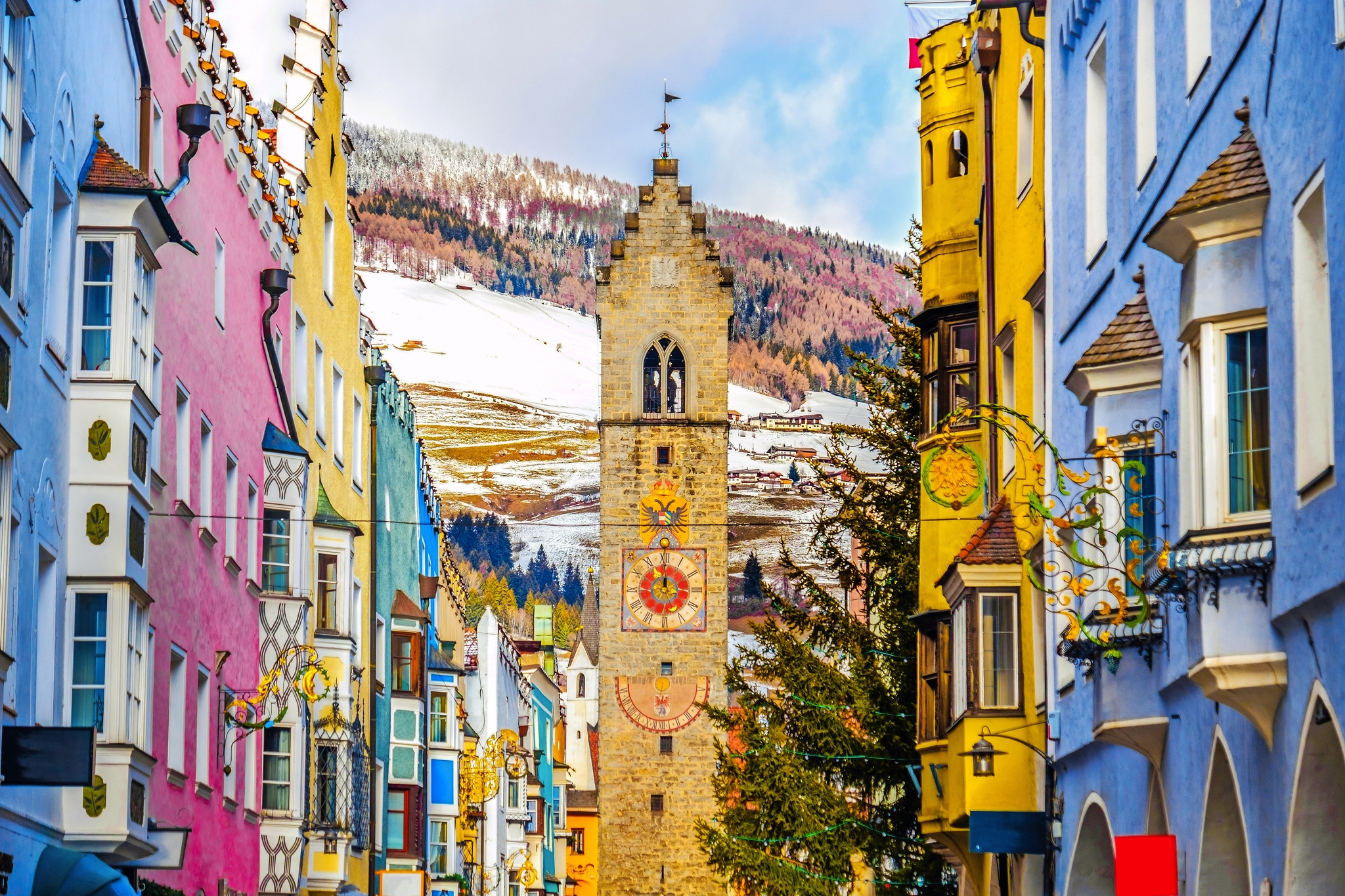 Bunte Häuserfassade und Turm in einer Alpenstadt im Winter.