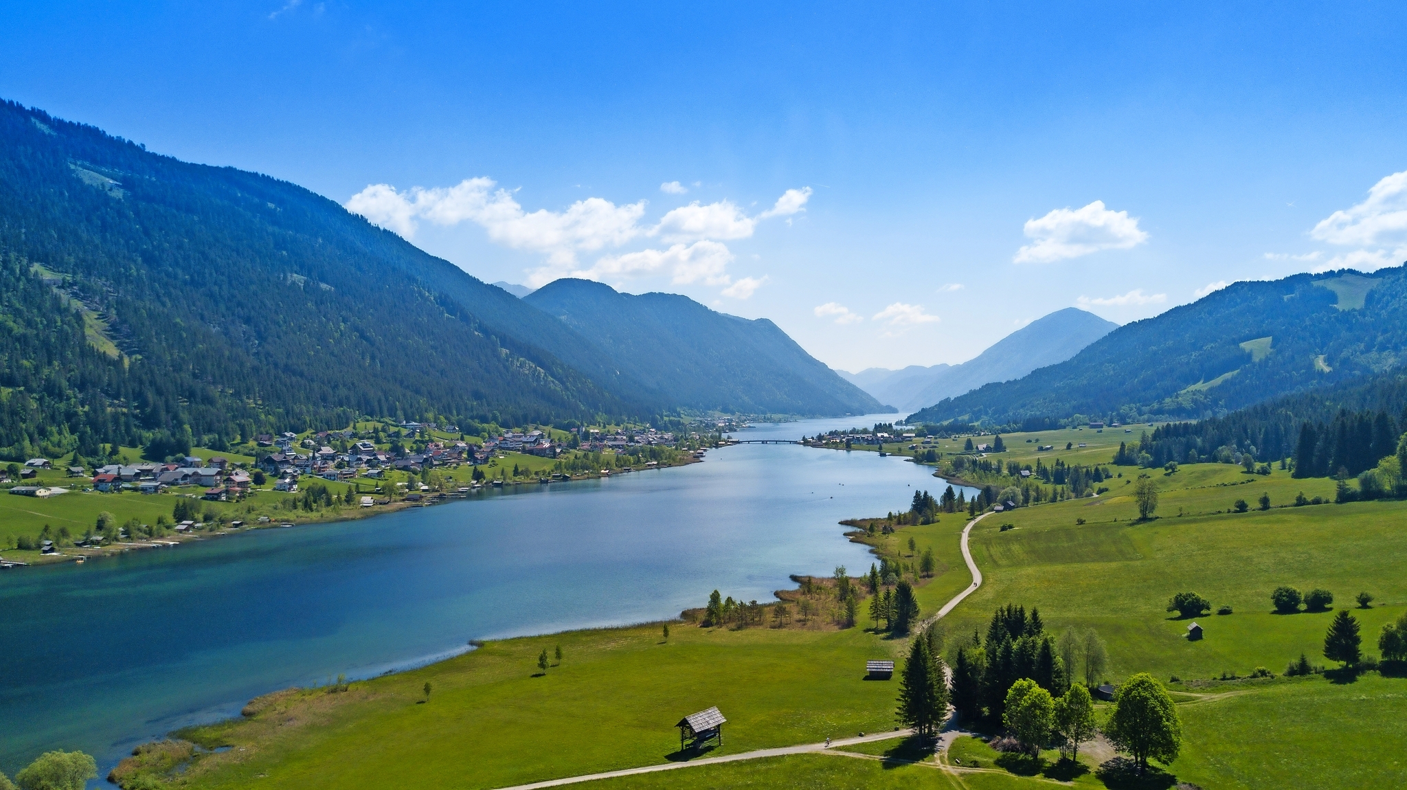 Mountainlandschaft mit See und Dorf im Tal bei klarem Himmel.